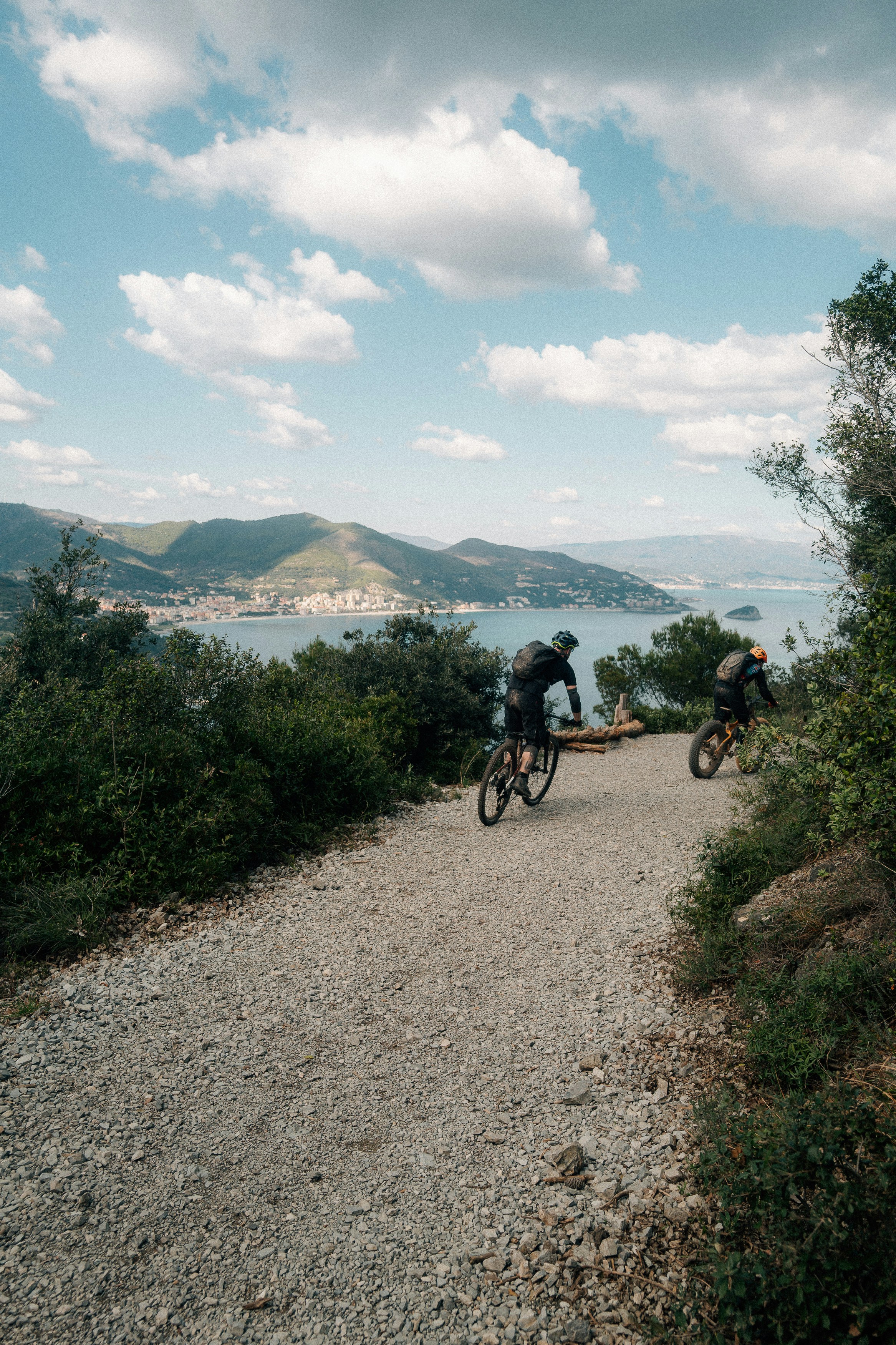 Two cyclists on a scenic coastal mountain trail.
