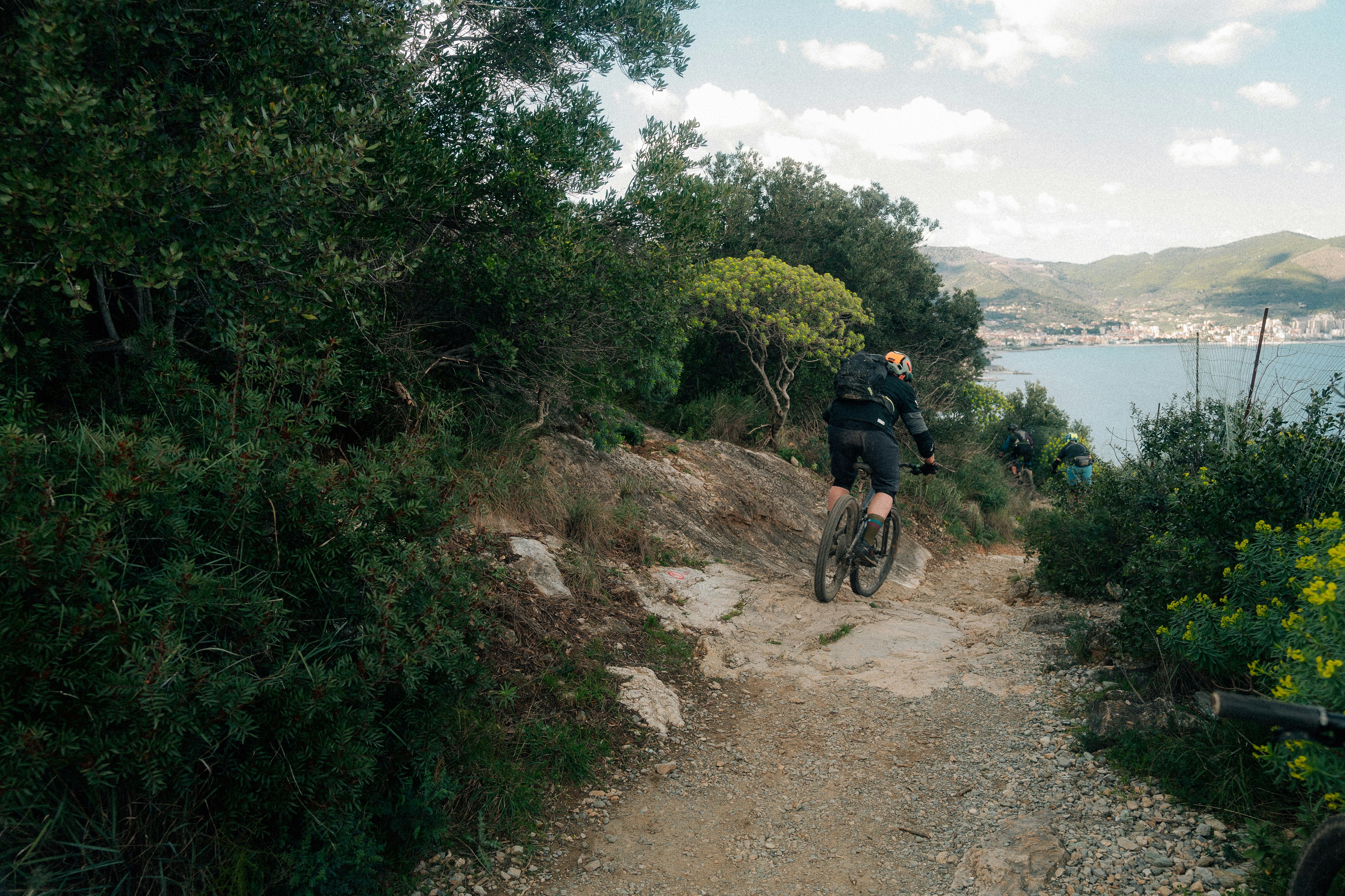 Cyclist on a rocky path overlooking the sea.