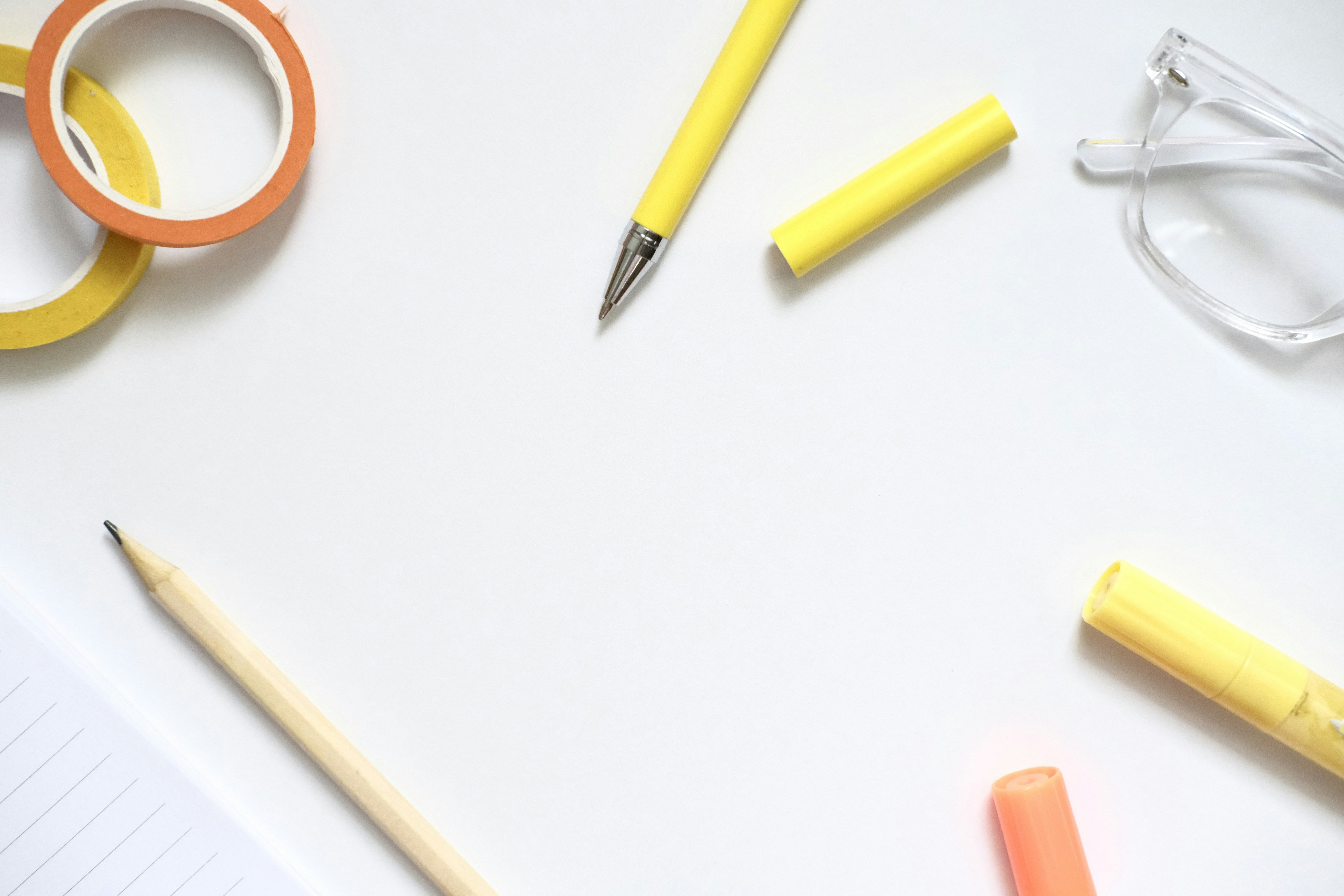 Yellow pen, pencil, tape, and glasses on white background.