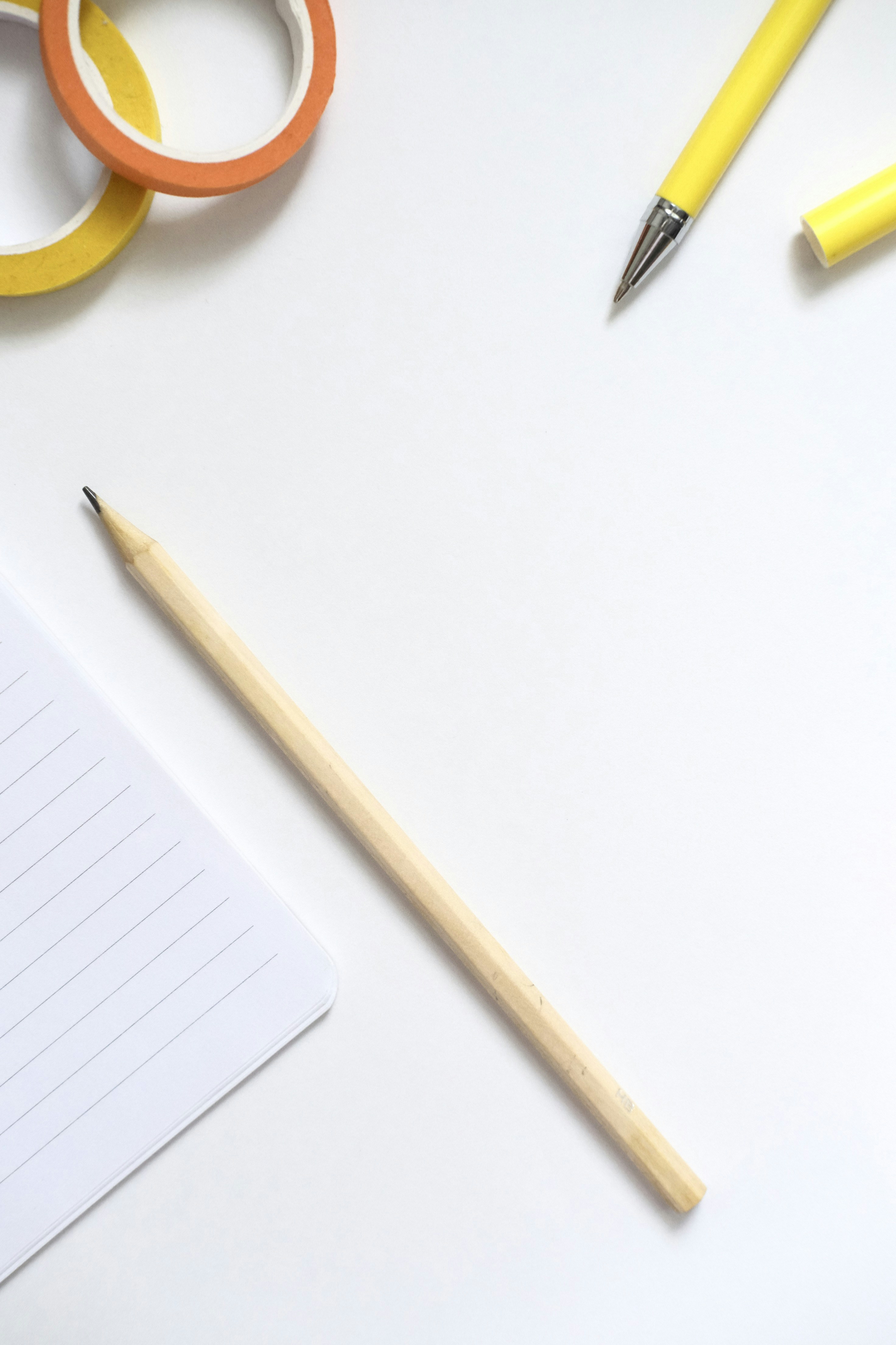 Notebook, pencil, and colorful tape on white surface
