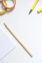 Notebook, pencil, and colorful tape on white surface