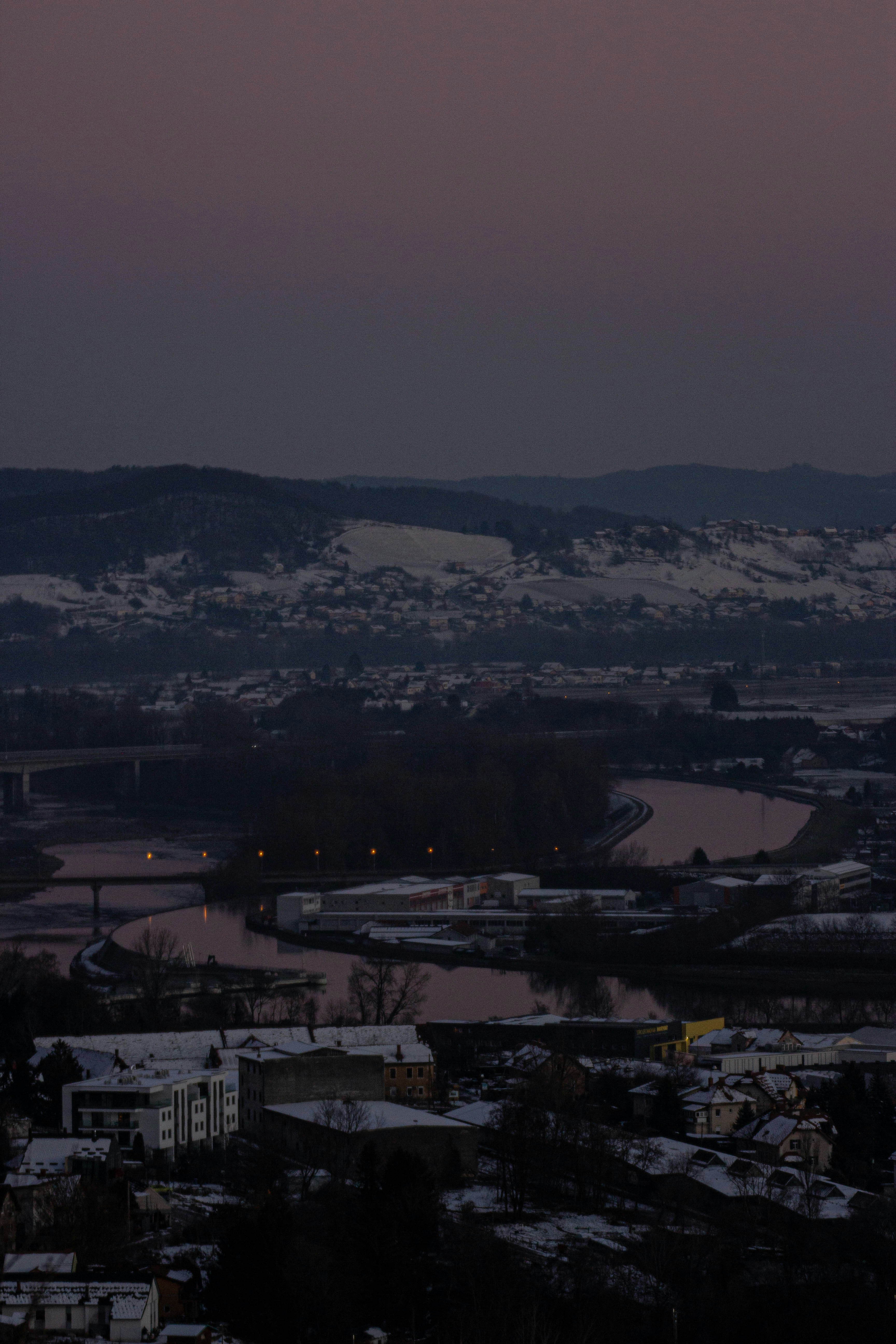 Snowy landscape with river and town at dusk