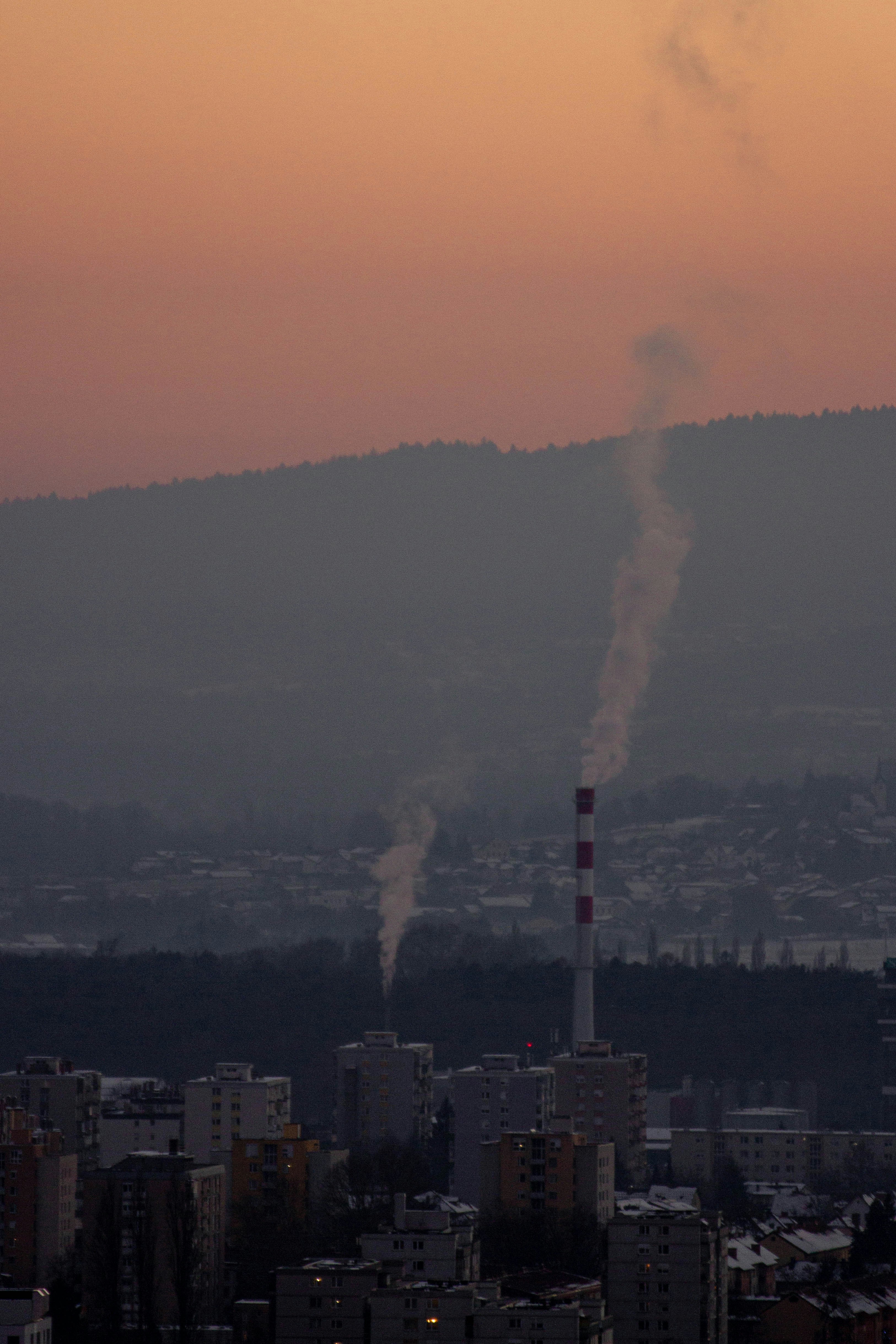 Industrial chimney emitting smoke against a hazy sky.
