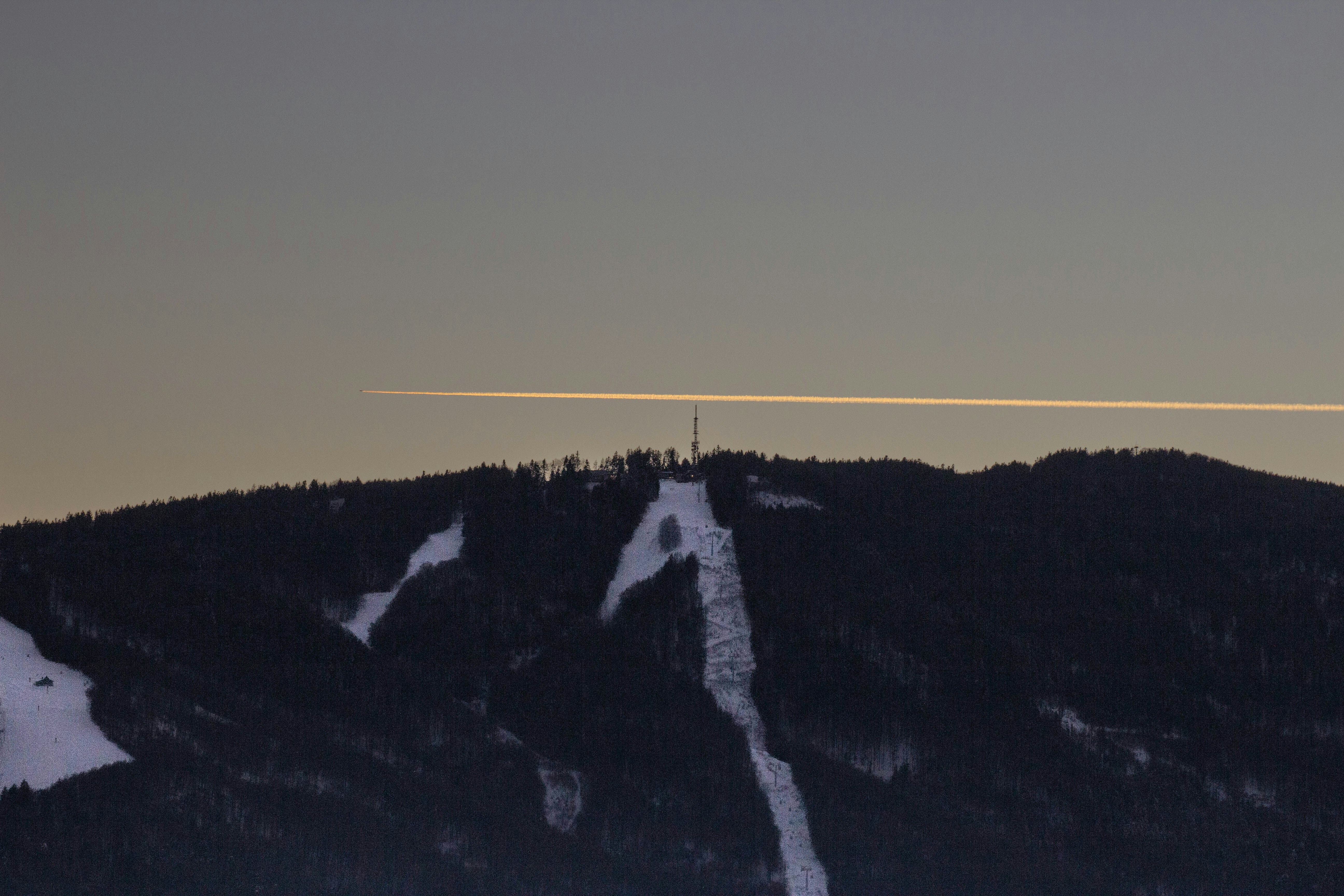 Airplane contrail over a snow-covered mountain peak.