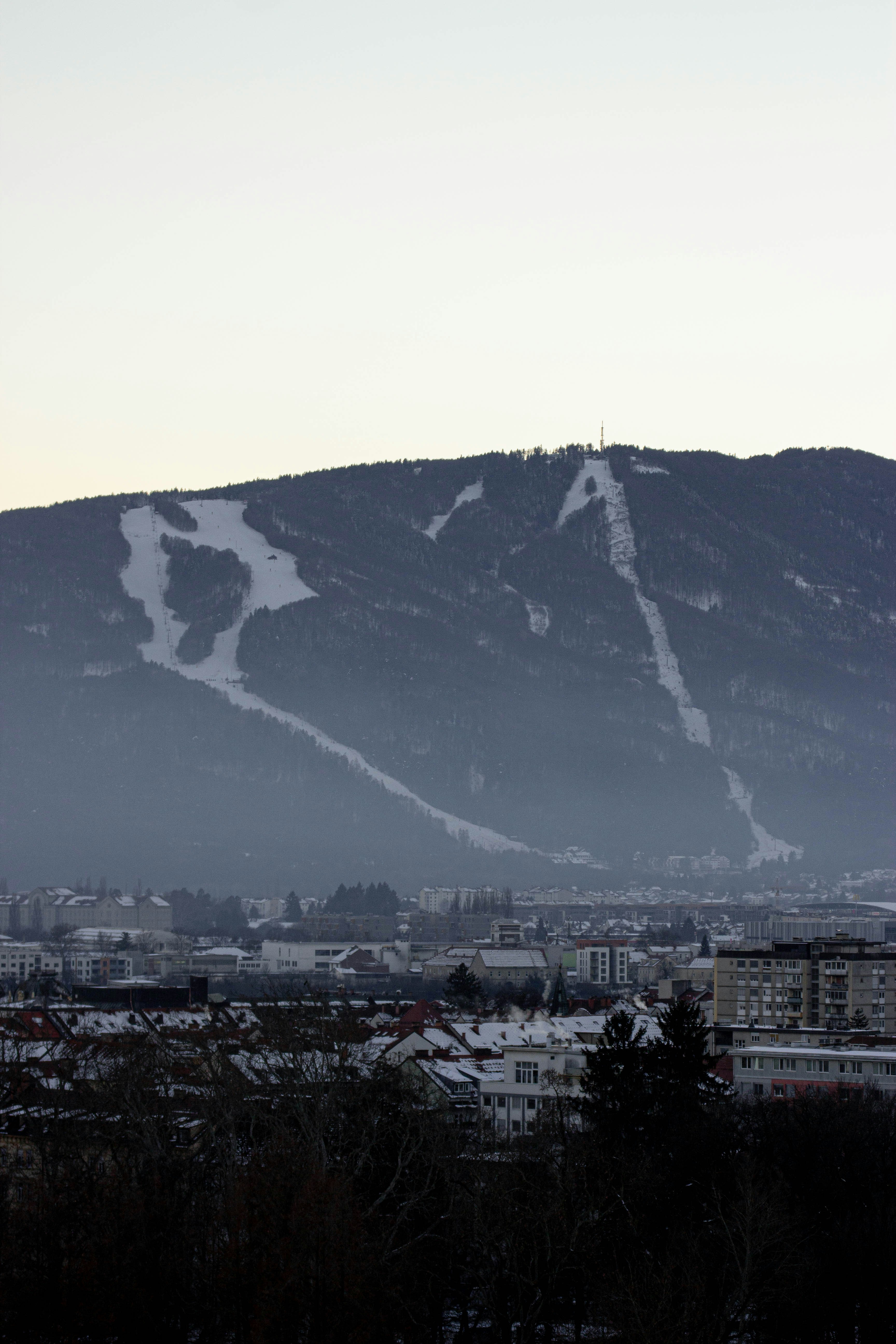 Snowy mountain slopes above a hazy town