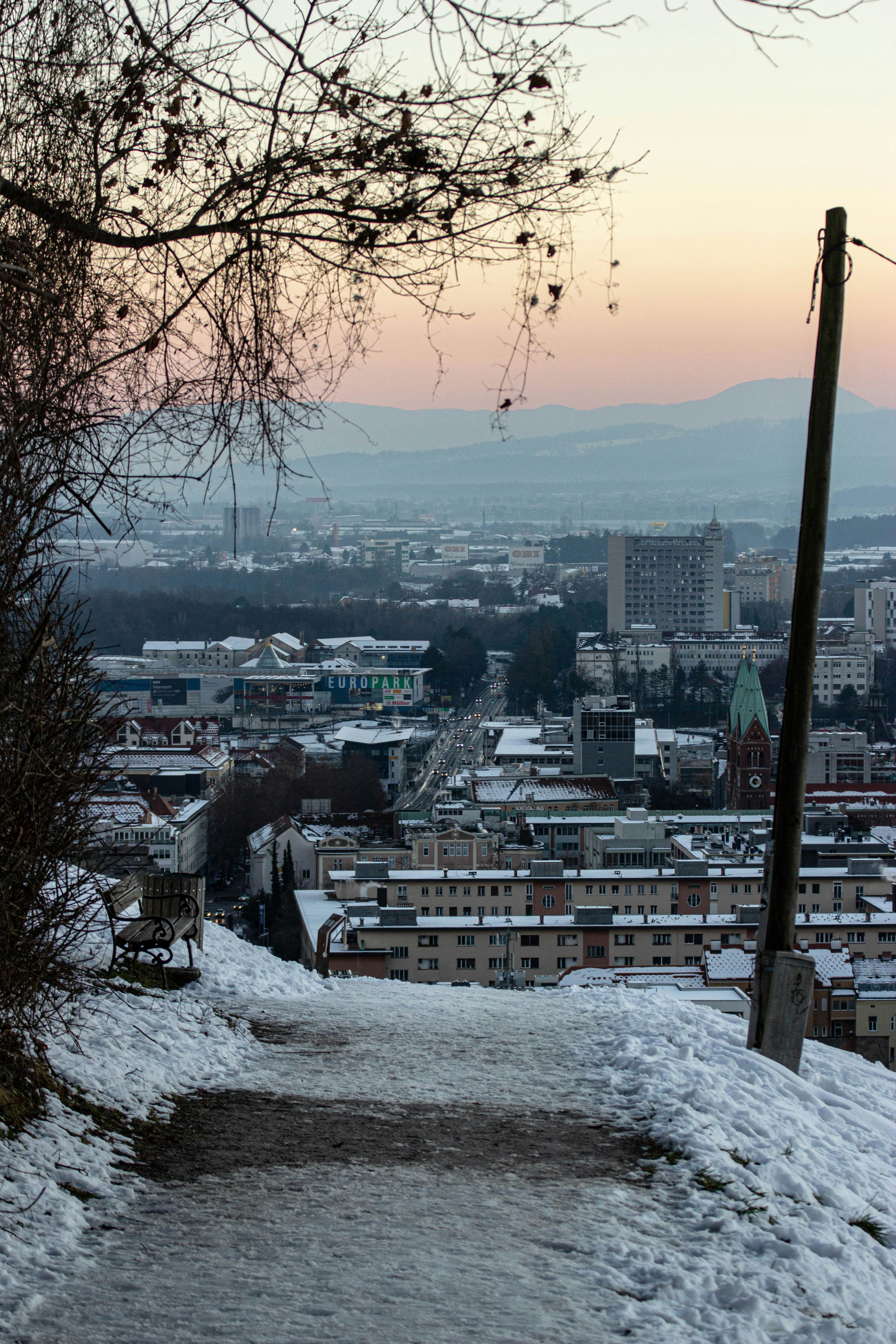 Snowy path overlooking a city at dusk