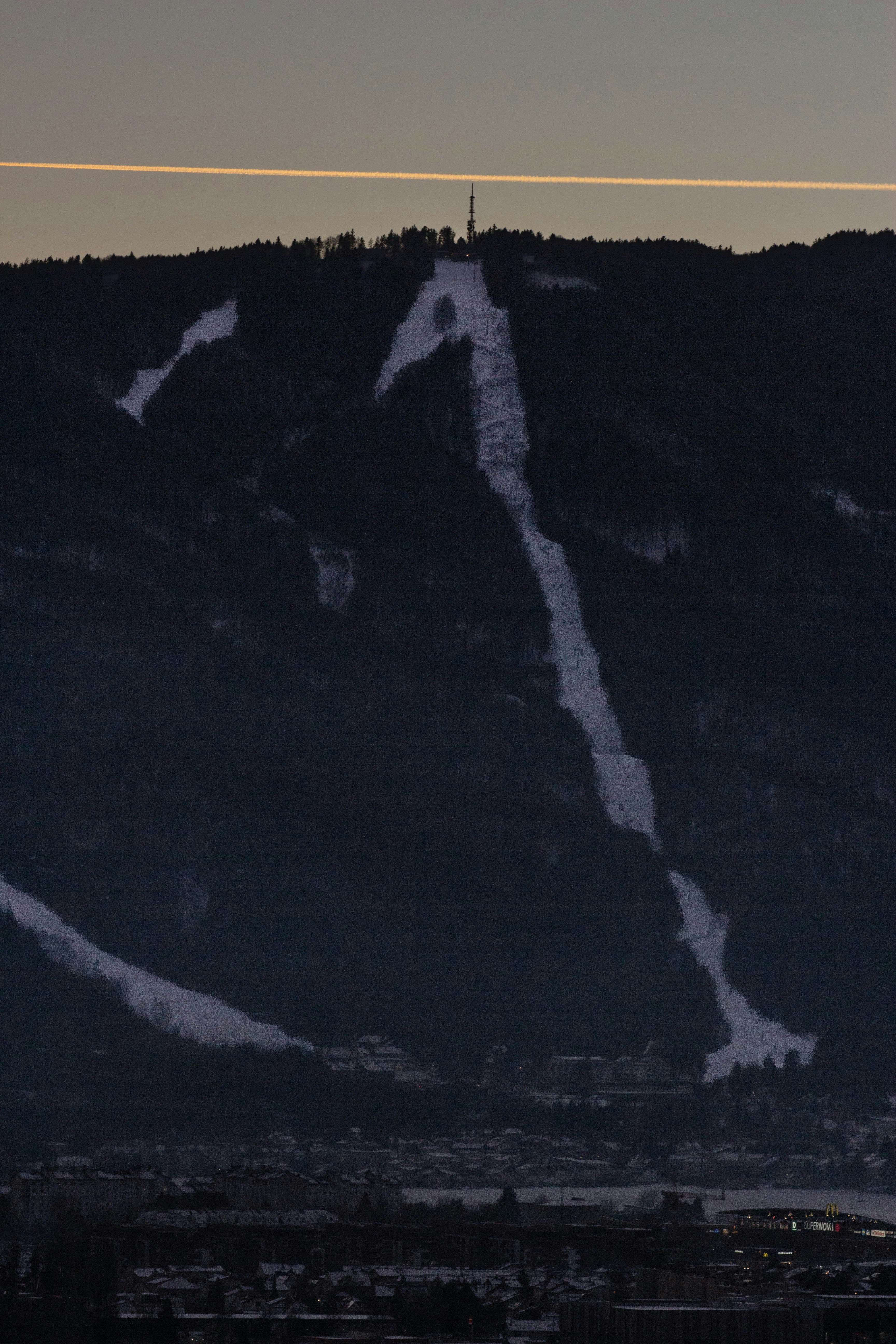 Snowy ski slope on a dark mountain at dusk