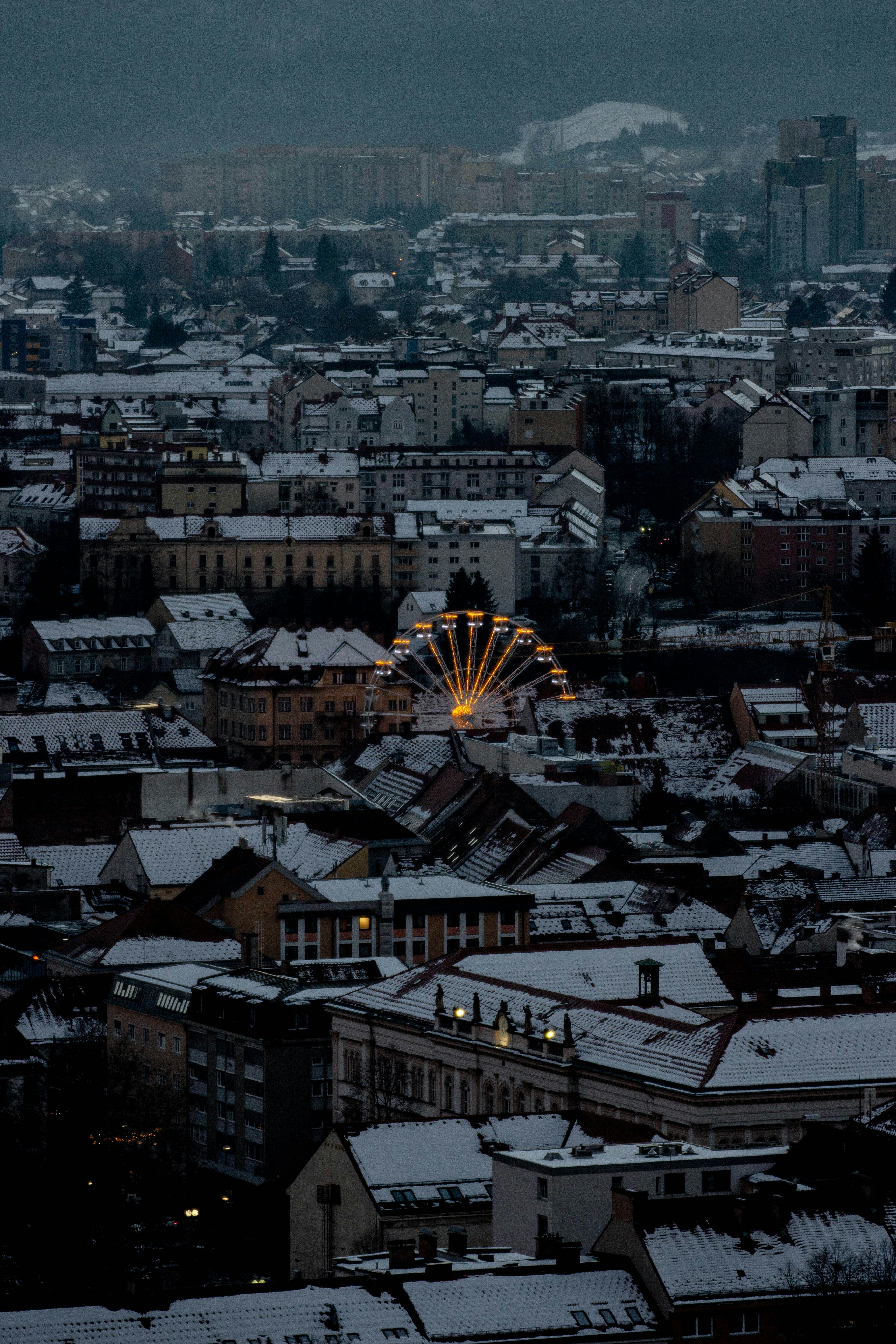 Ferris wheel illuminated in a snowy city at dusk