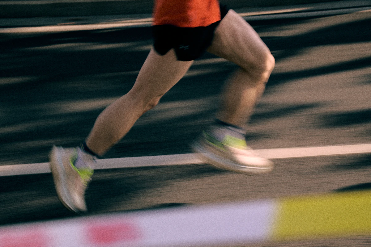 Close-up of a runner's legs and shoes in motion on a track, blurred, no face visible