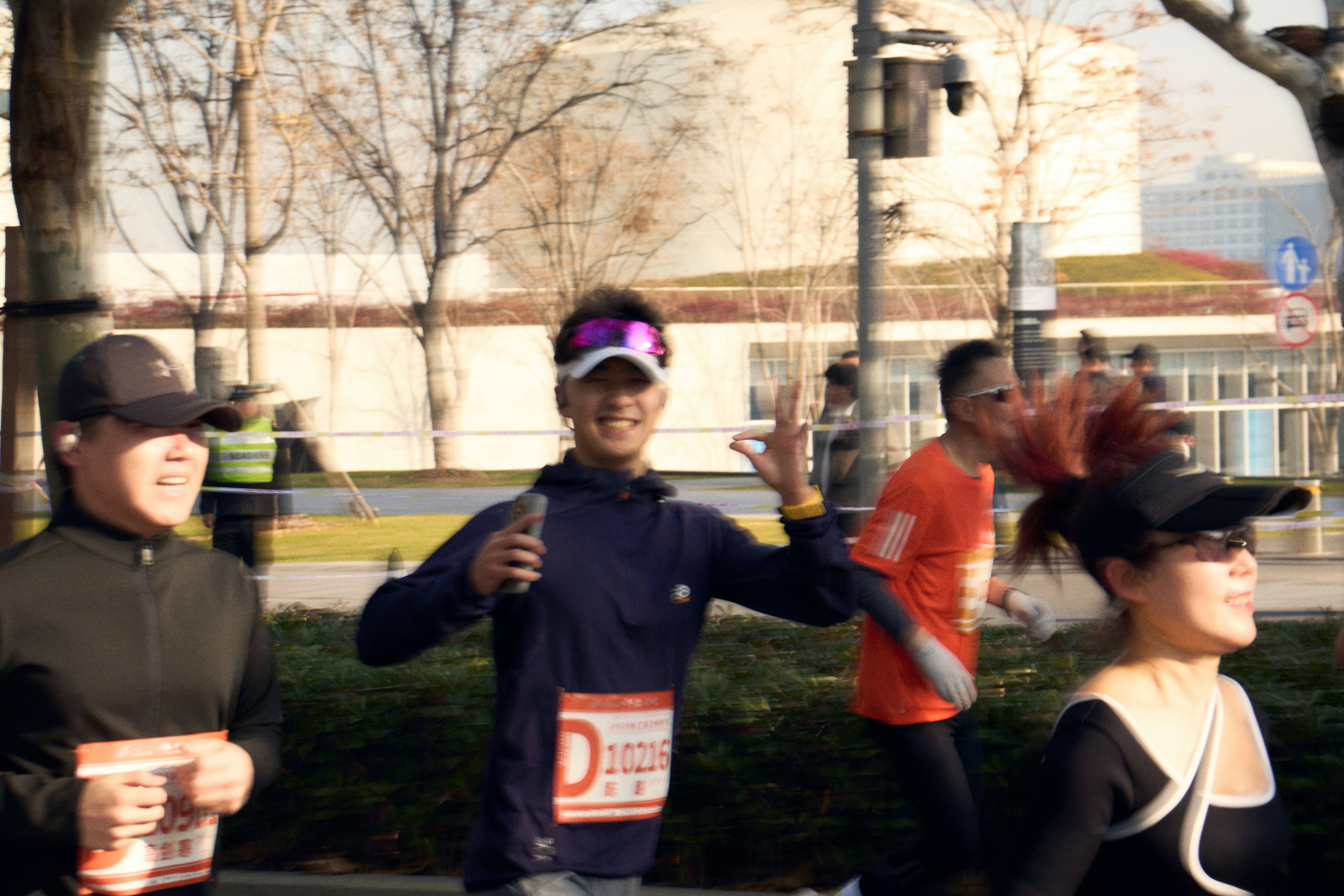 Un homme courant un marathon, souriant et faisant le signe de paix.
