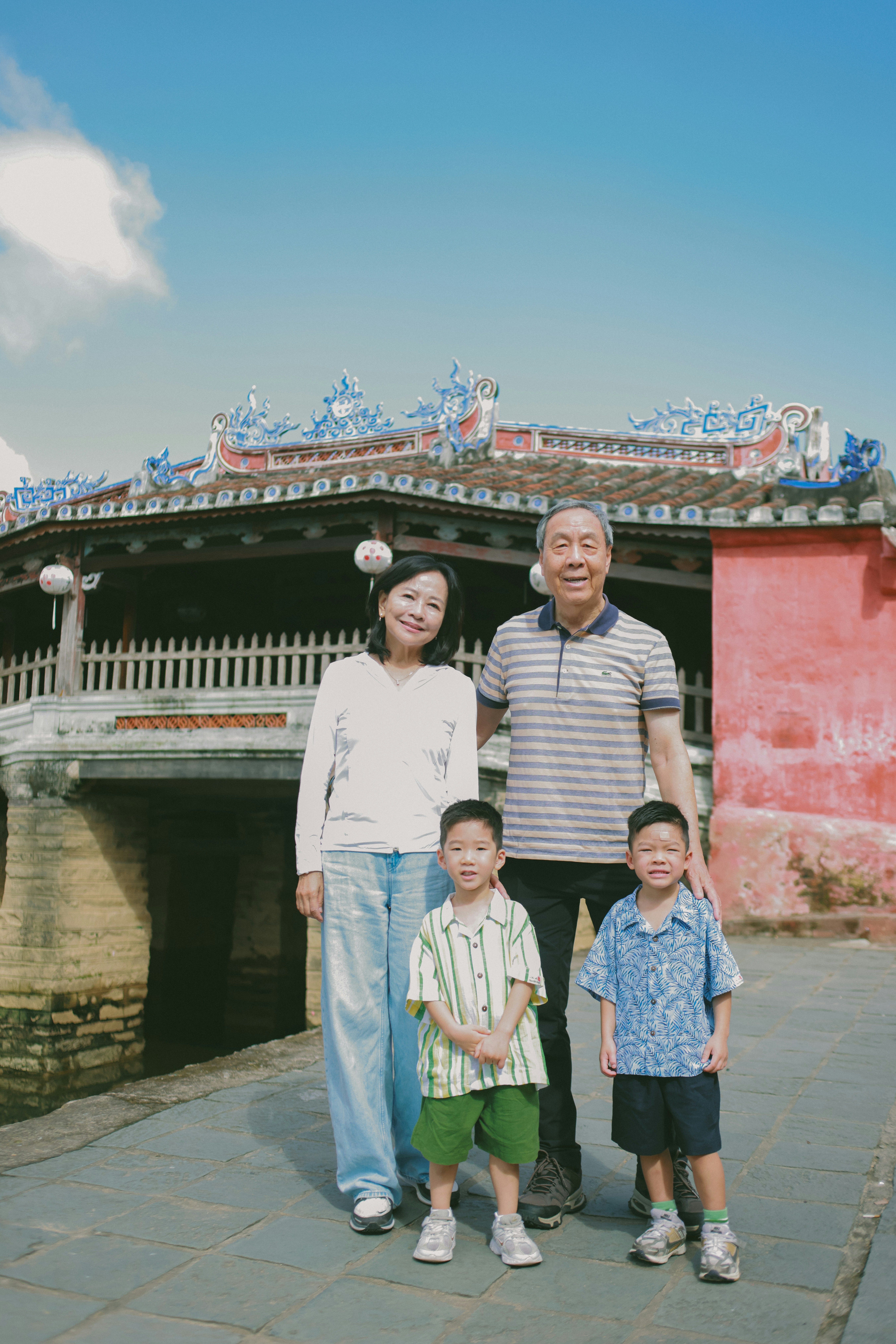 A family poses in front of a historic bridge.