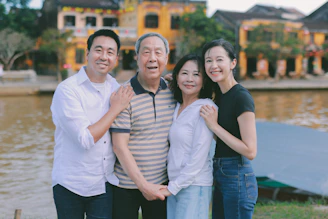 A multigenerational family posing outdoors by a river.