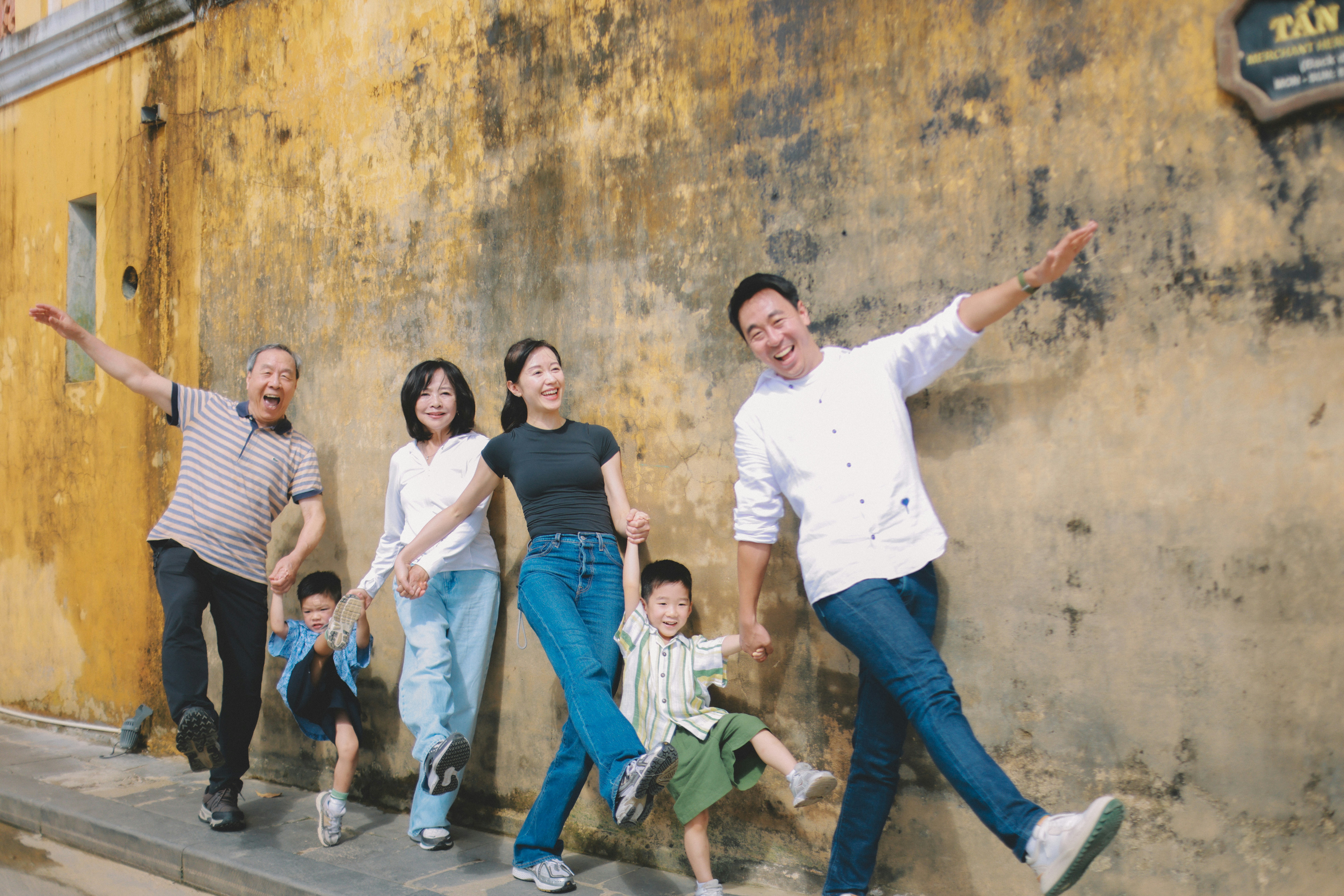 Una famiglia felice posa davanti a un muro giallo.