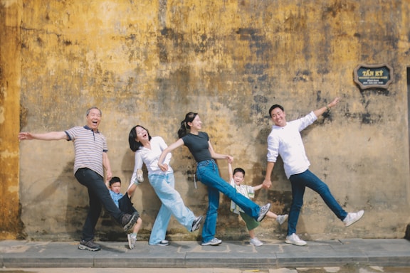 Family posing playfully against a textured wall.