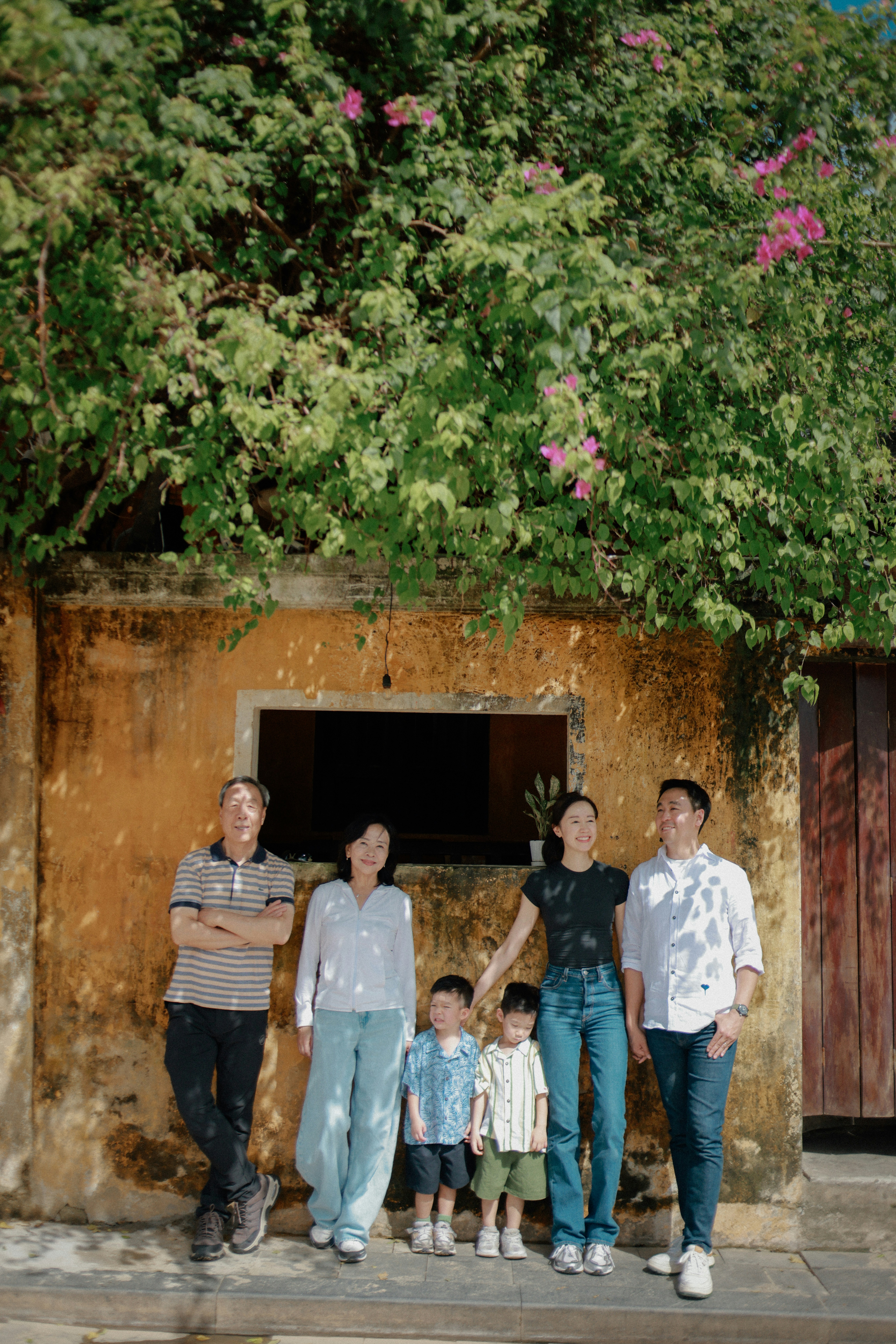 A multi-generational family poses against a textured wall.