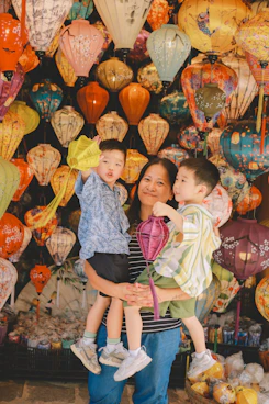 Woman holding two young boys with lanterns