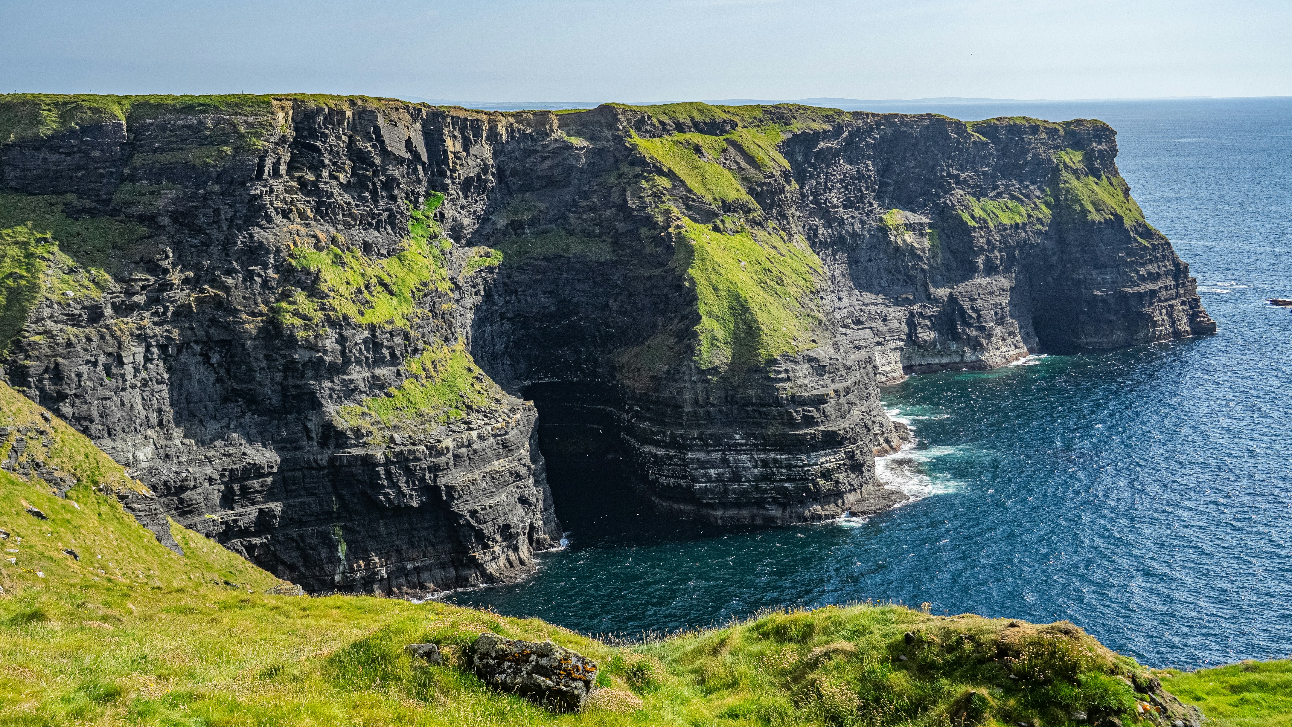 Scogliere drammatiche incontrano l'oceano blu sotto un cielo luminoso