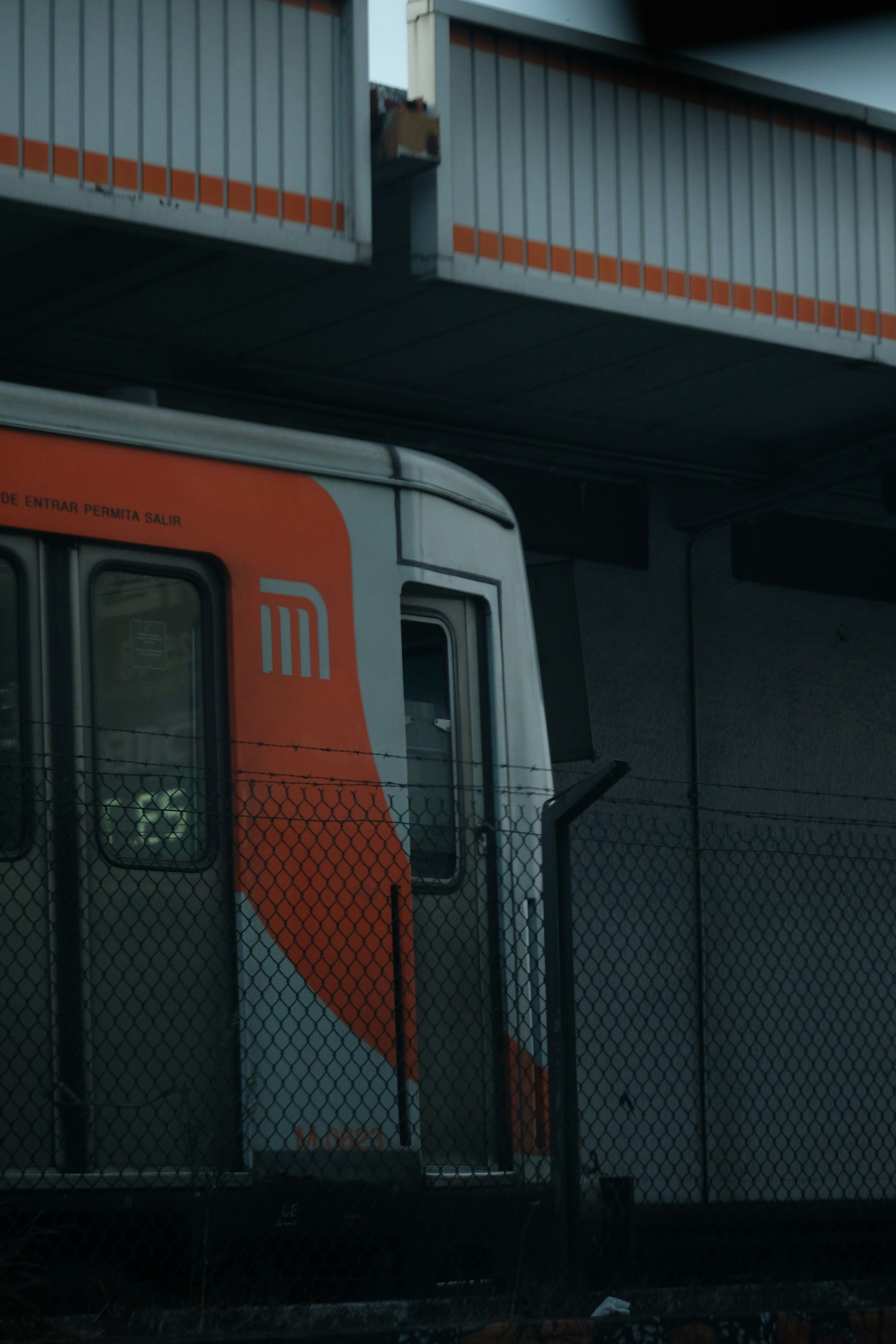 A train with an orange stripe at a station.
