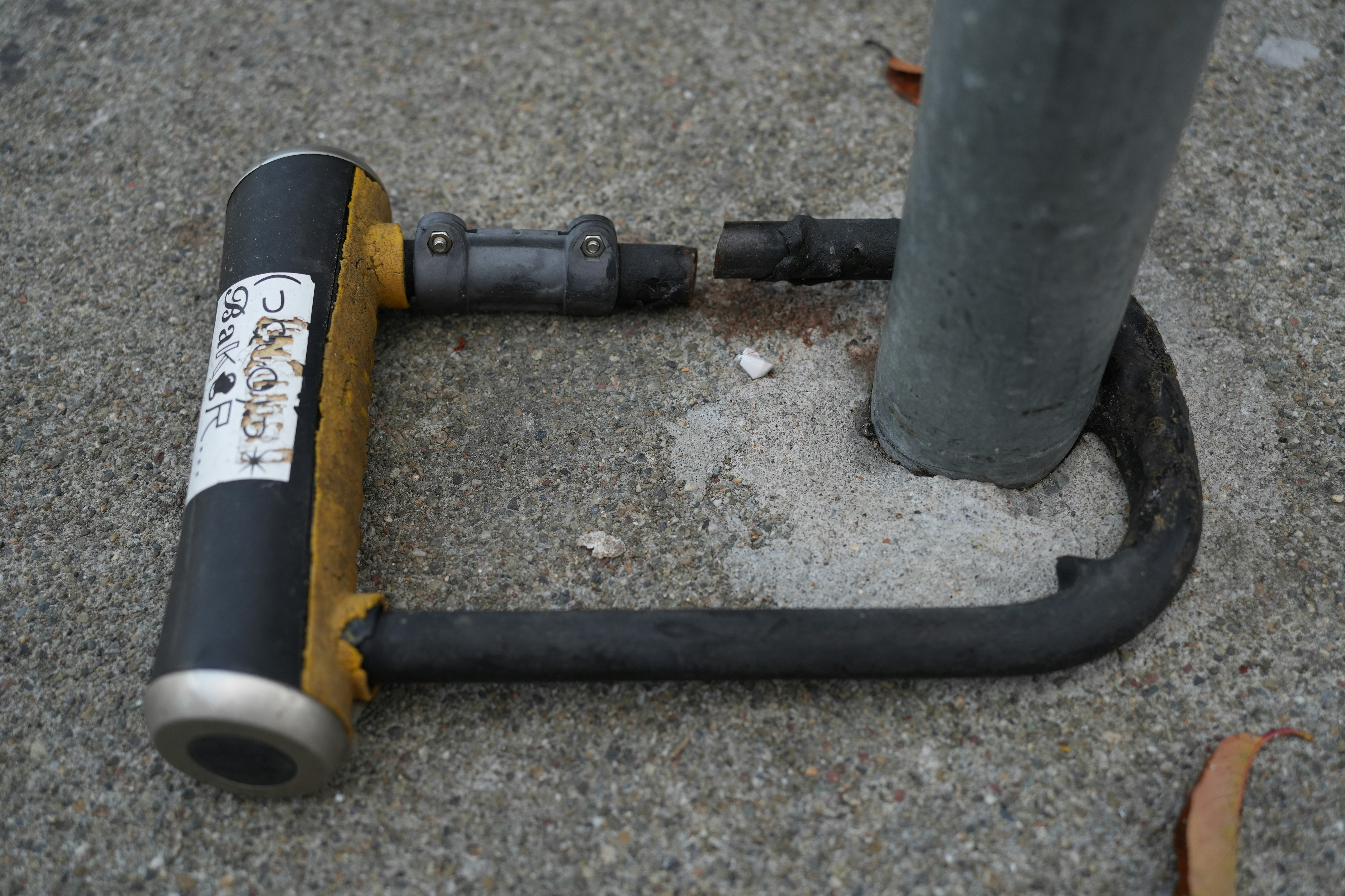 A cut u-lock lying on concrete ground.