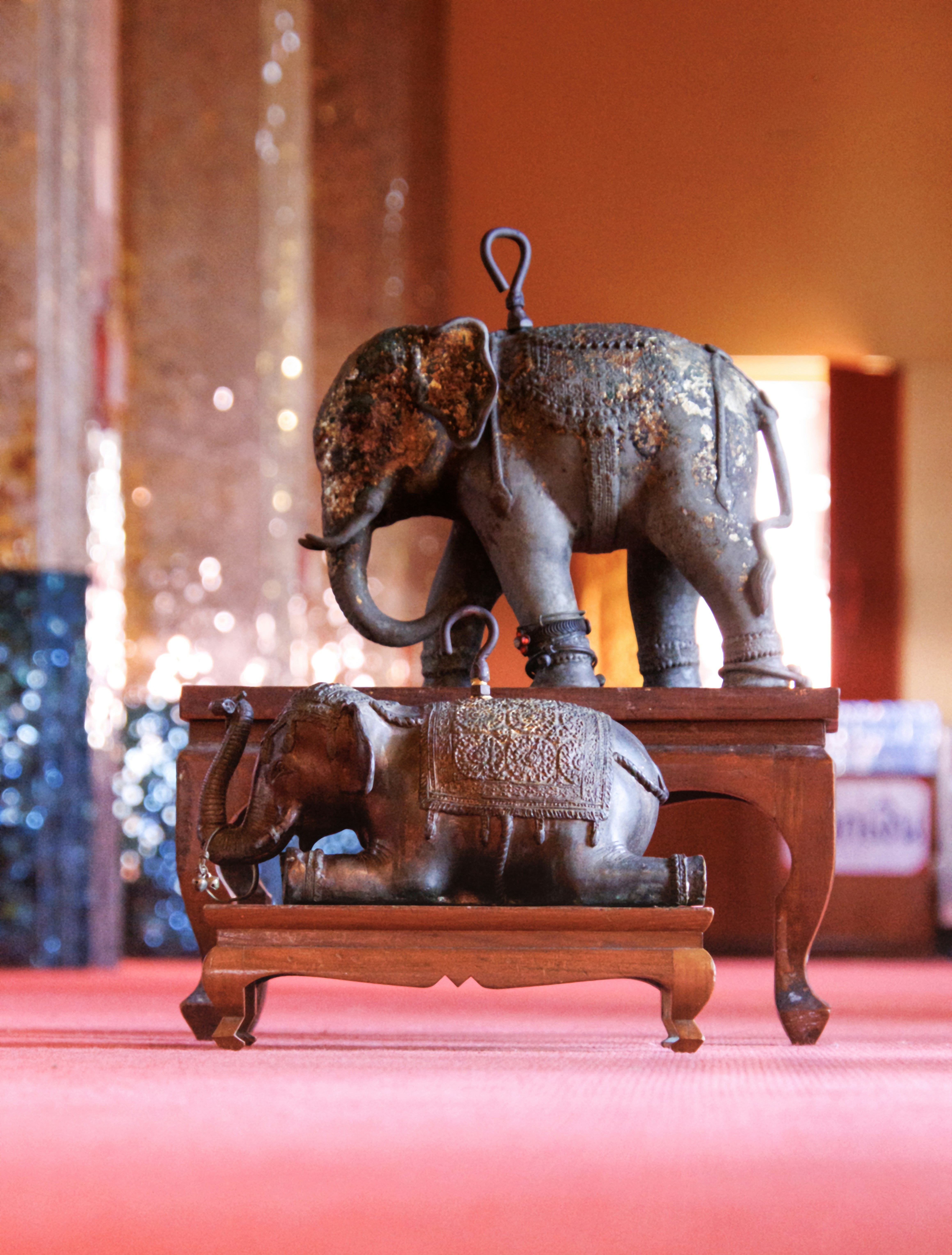 Two ornate elephant statues on wooden stands