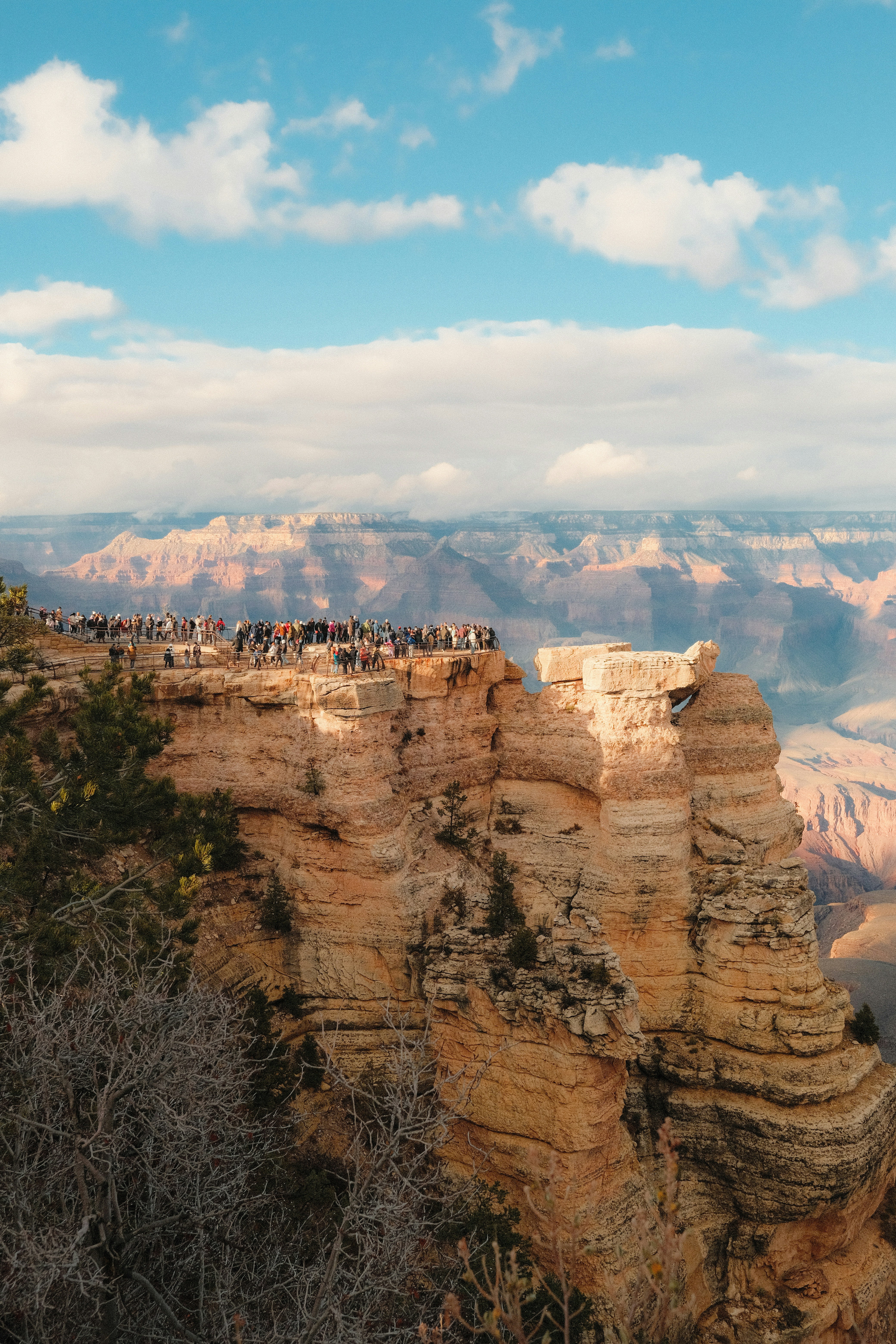 Touristen auf einer Klippe mit Blick auf eine weite Schluchtlandschaft.