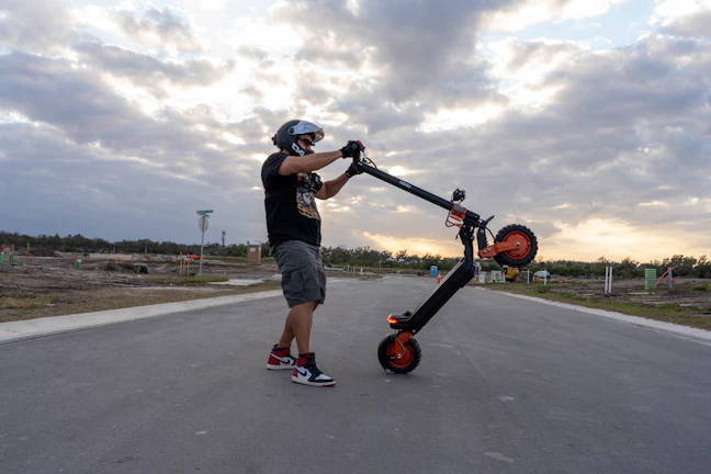 Man in helmet holding electric scooter outdoors