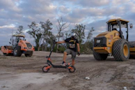 Man with electric scooter near construction vehicles