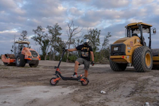 Man with electric scooter near construction vehicles