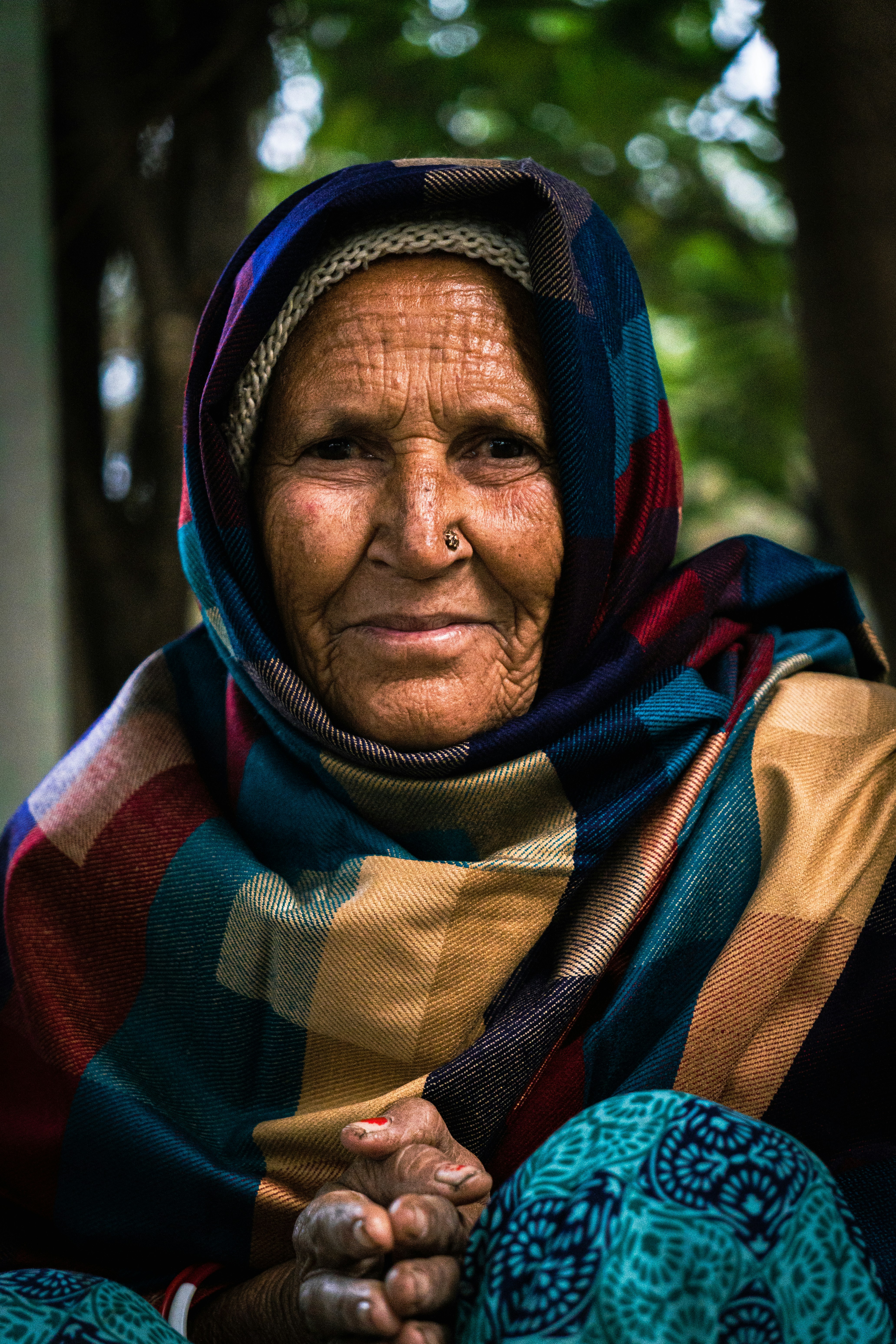 Elderly woman with a colorful headscarf and nose ring.