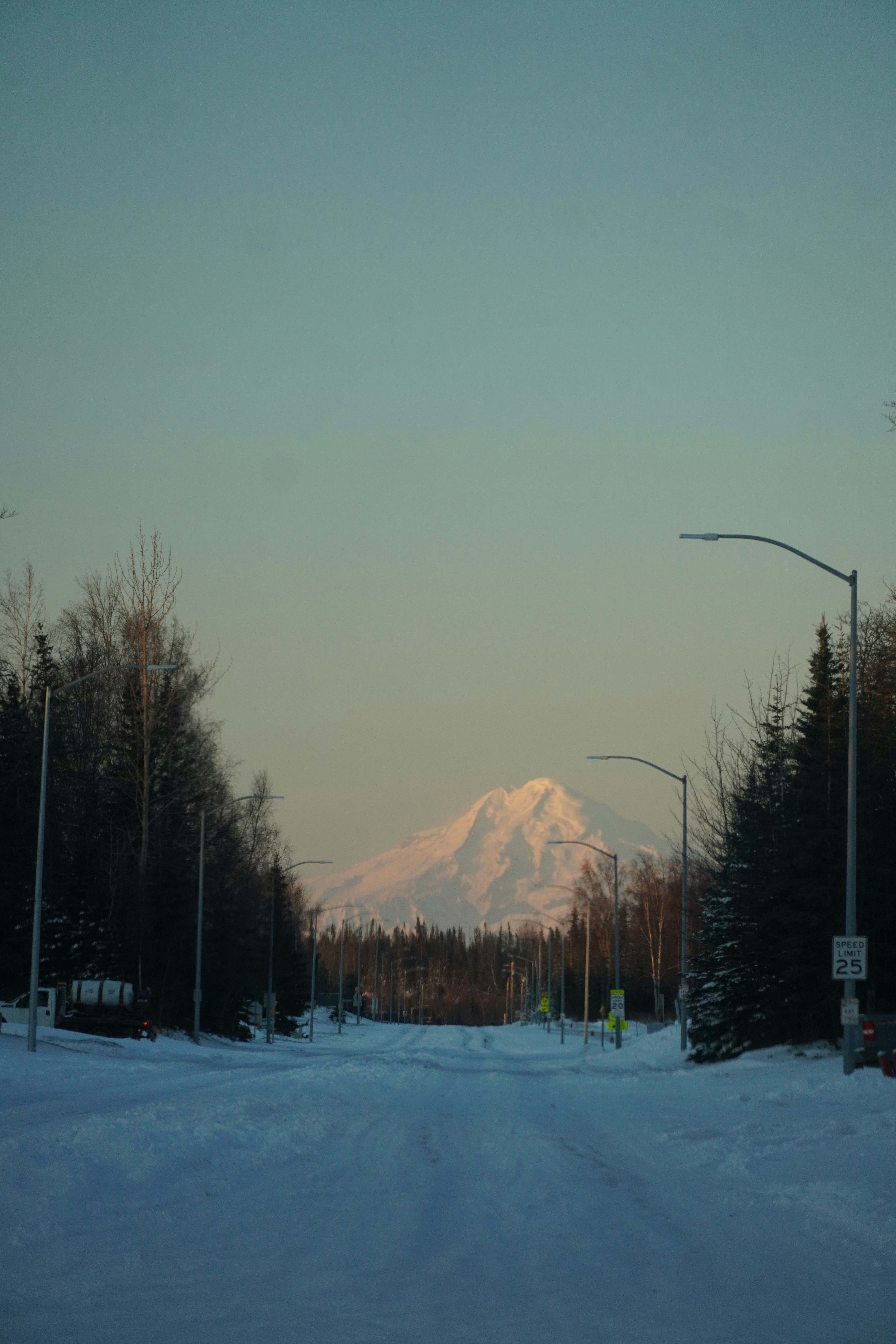 Snowy mountain peak visible from a snow-covered road.