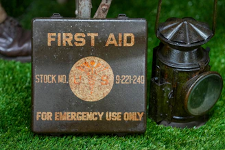 Vintage first aid kit and lantern on grass