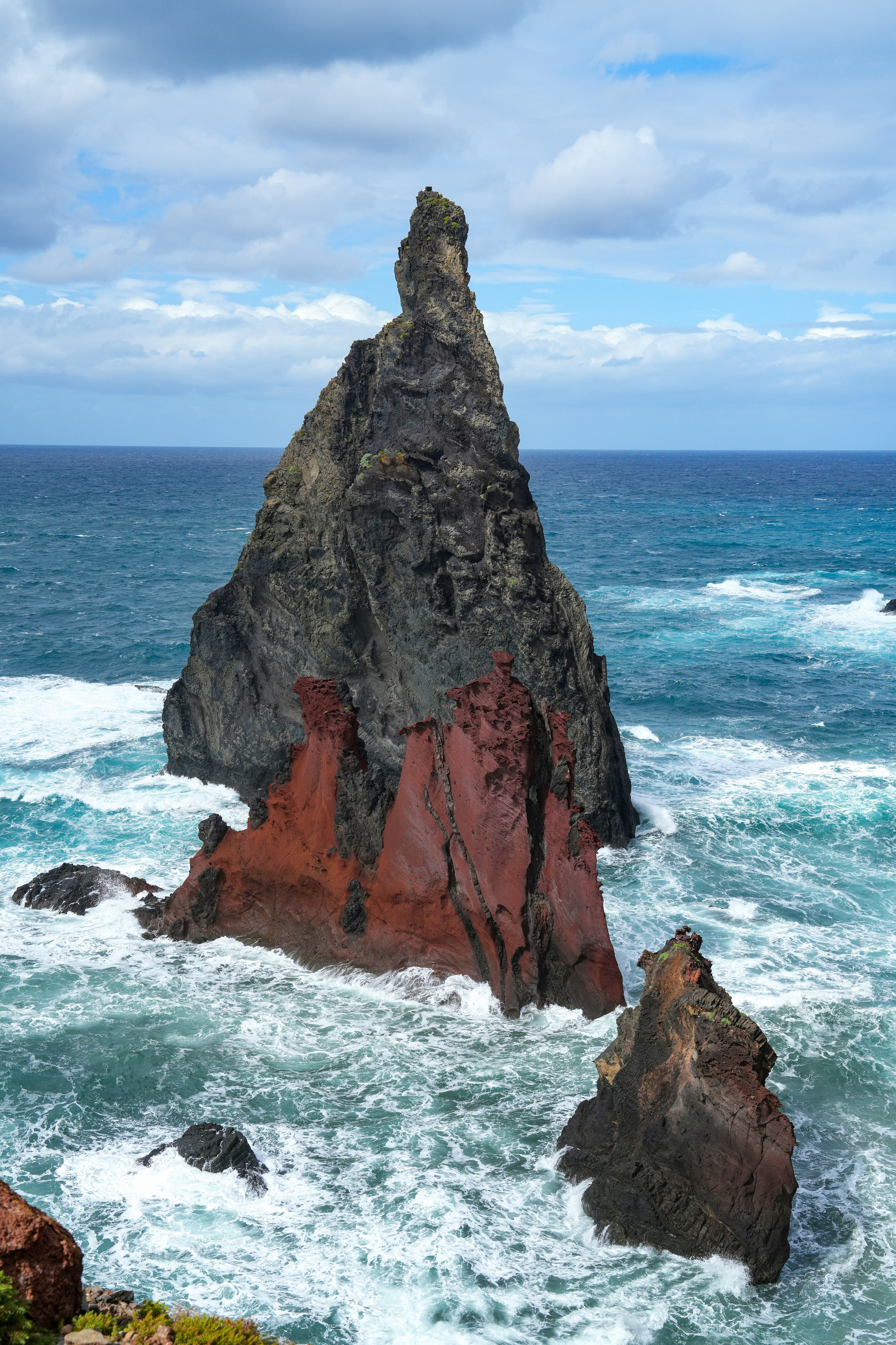 Jagged rock formations rise from the turbulent ocean waves.