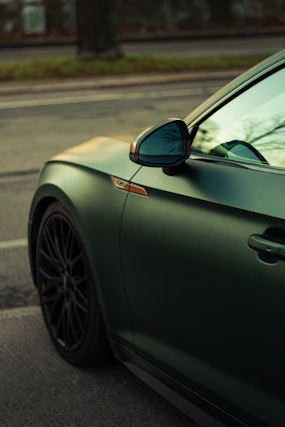 Matte dark green car parked on asphalt street.