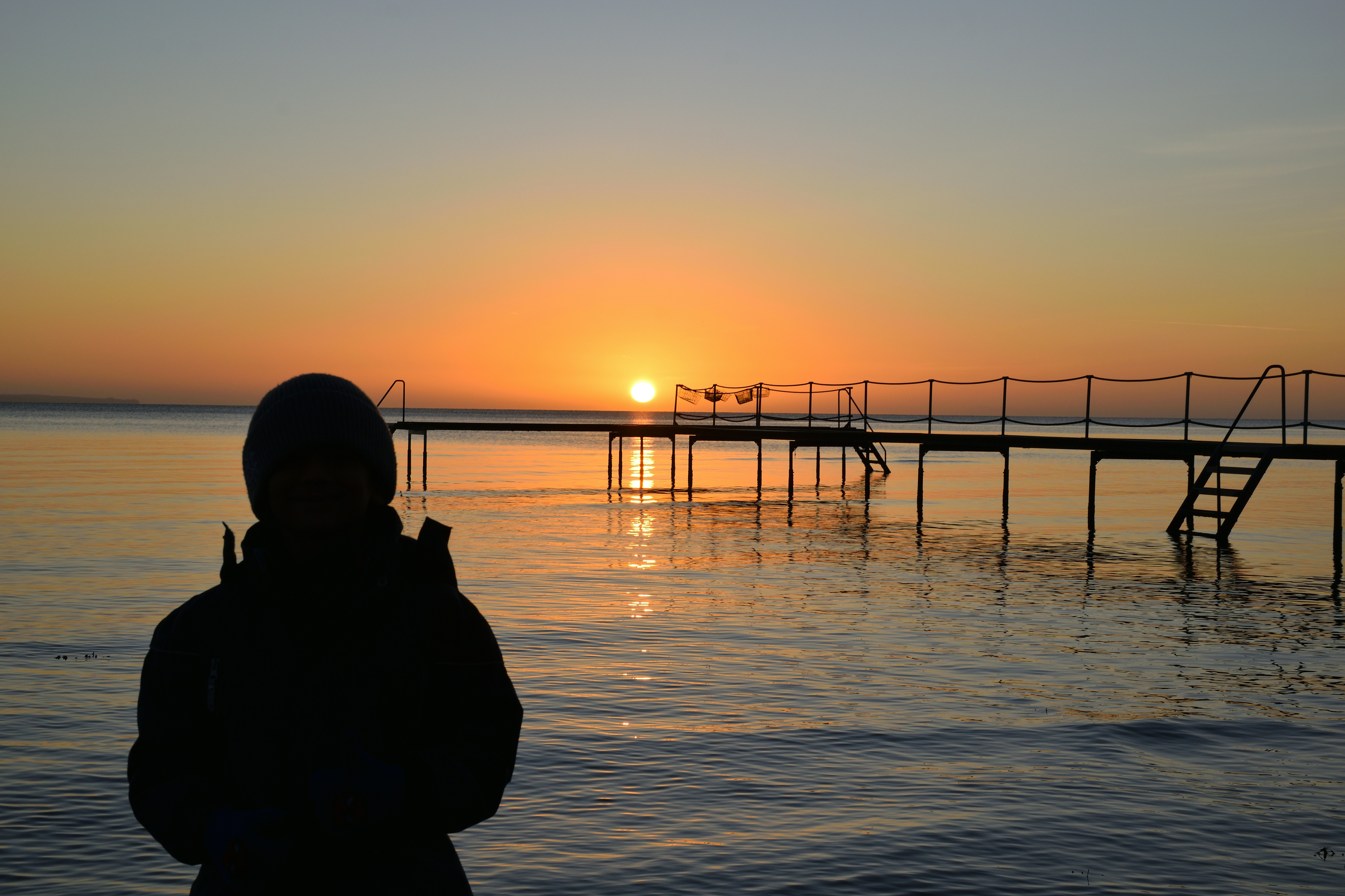 Silhouette of person watching a sunset over the ocean.