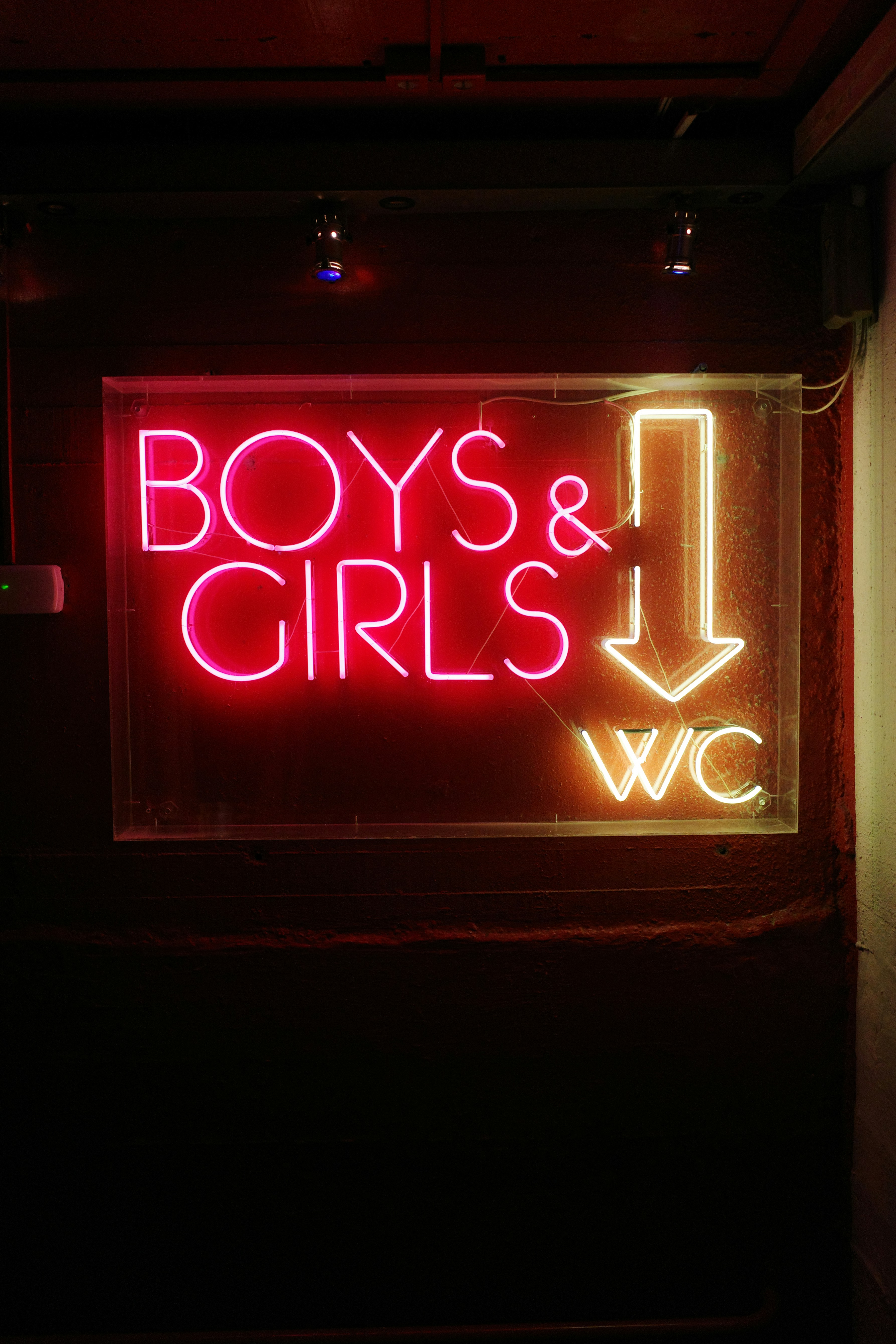 Neon sign for boys and girls restroom with arrow.