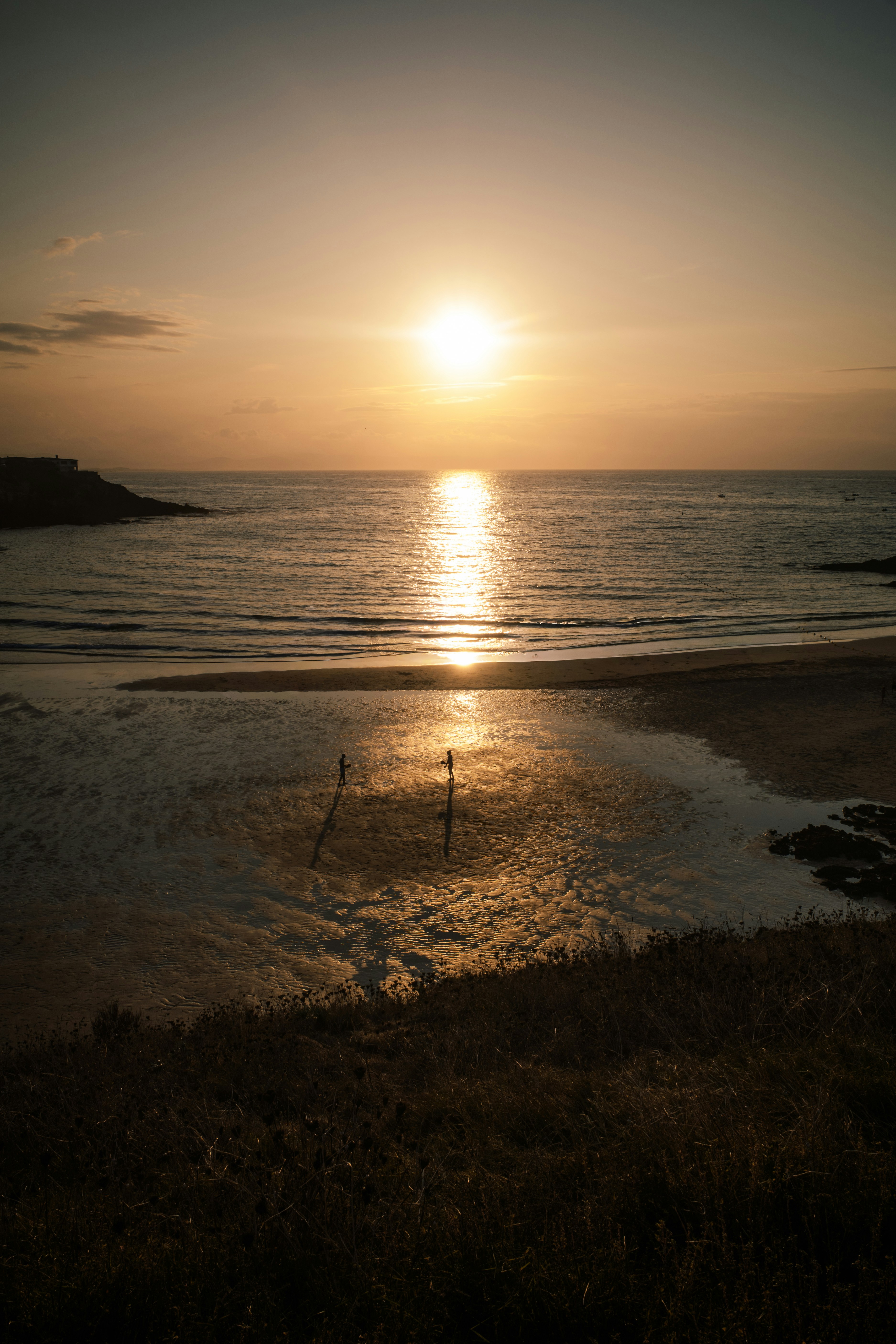 Sunset over a calm ocean with two people