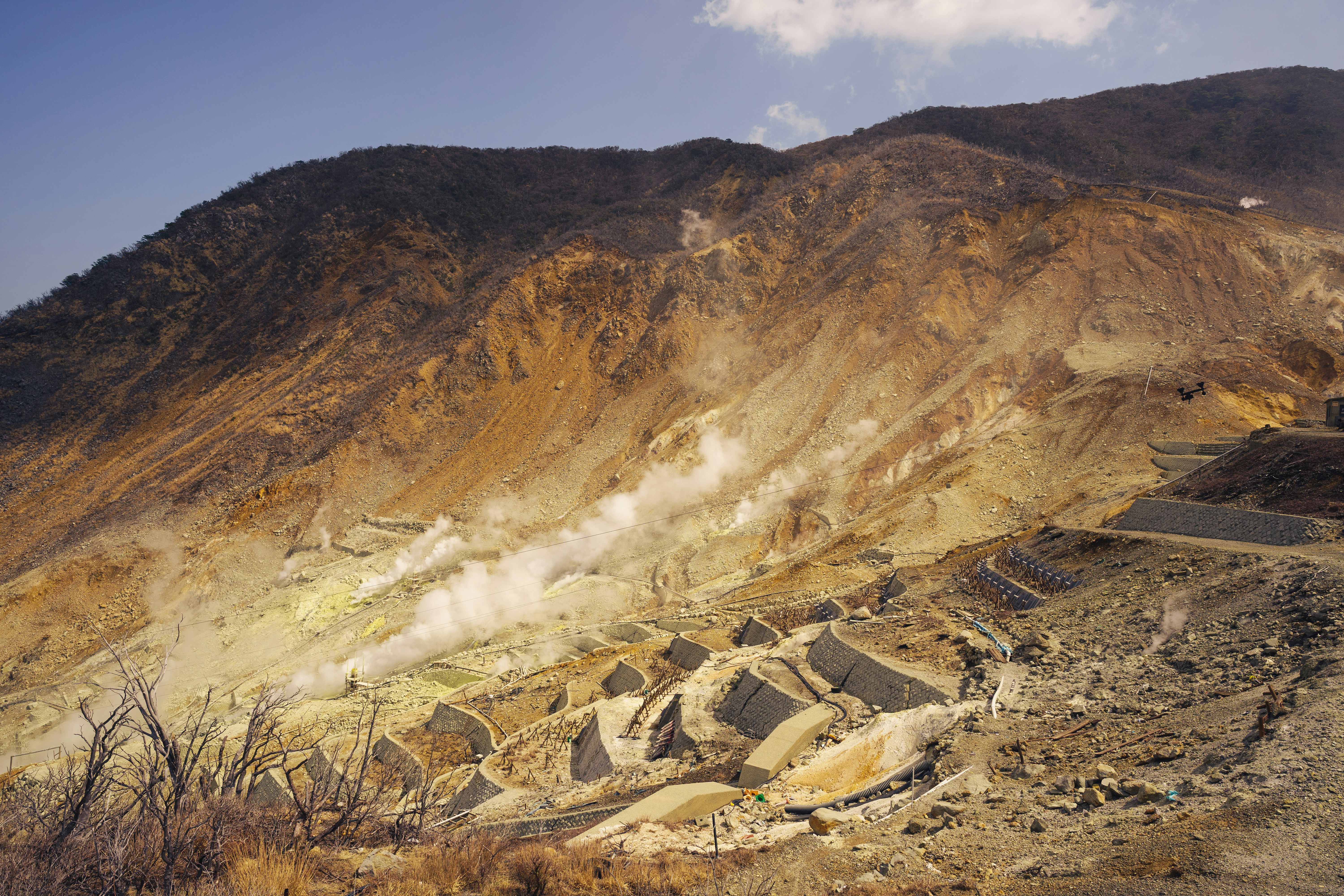 Volcanic landscape with steaming vents and terraced slopes.