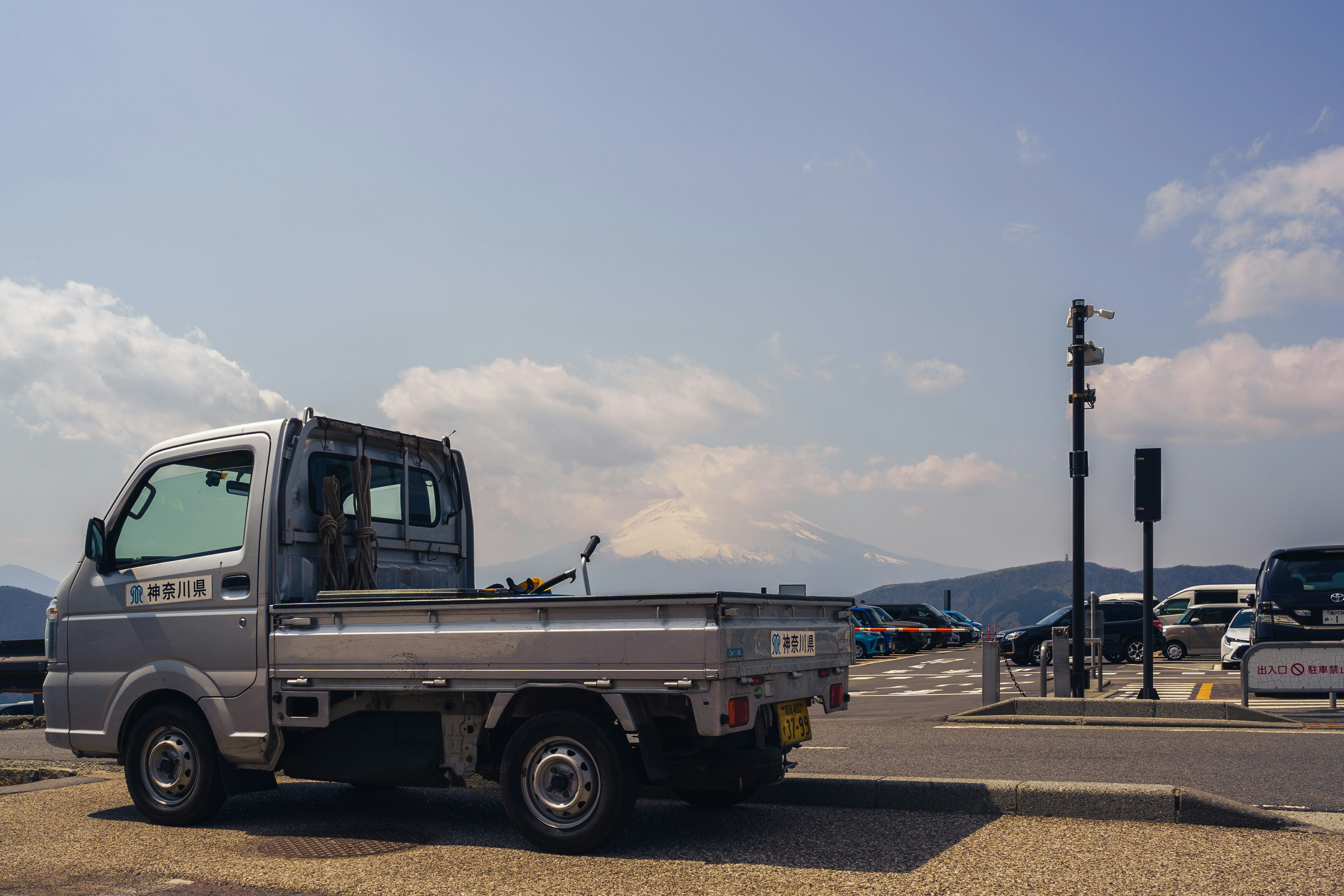 Silver flatbed truck parked with mountain view.