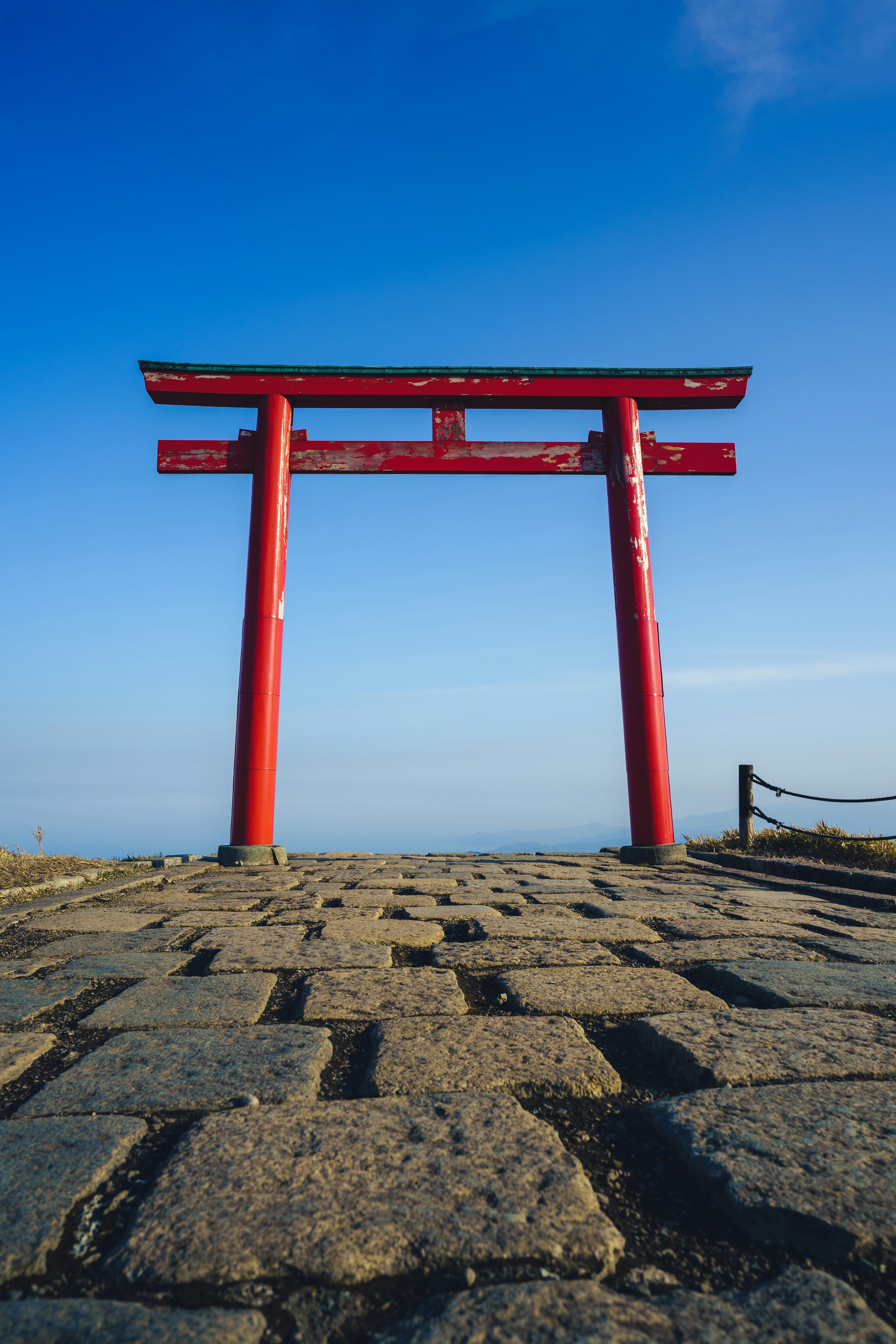 A vibrant red torii gate against a clear blue sky