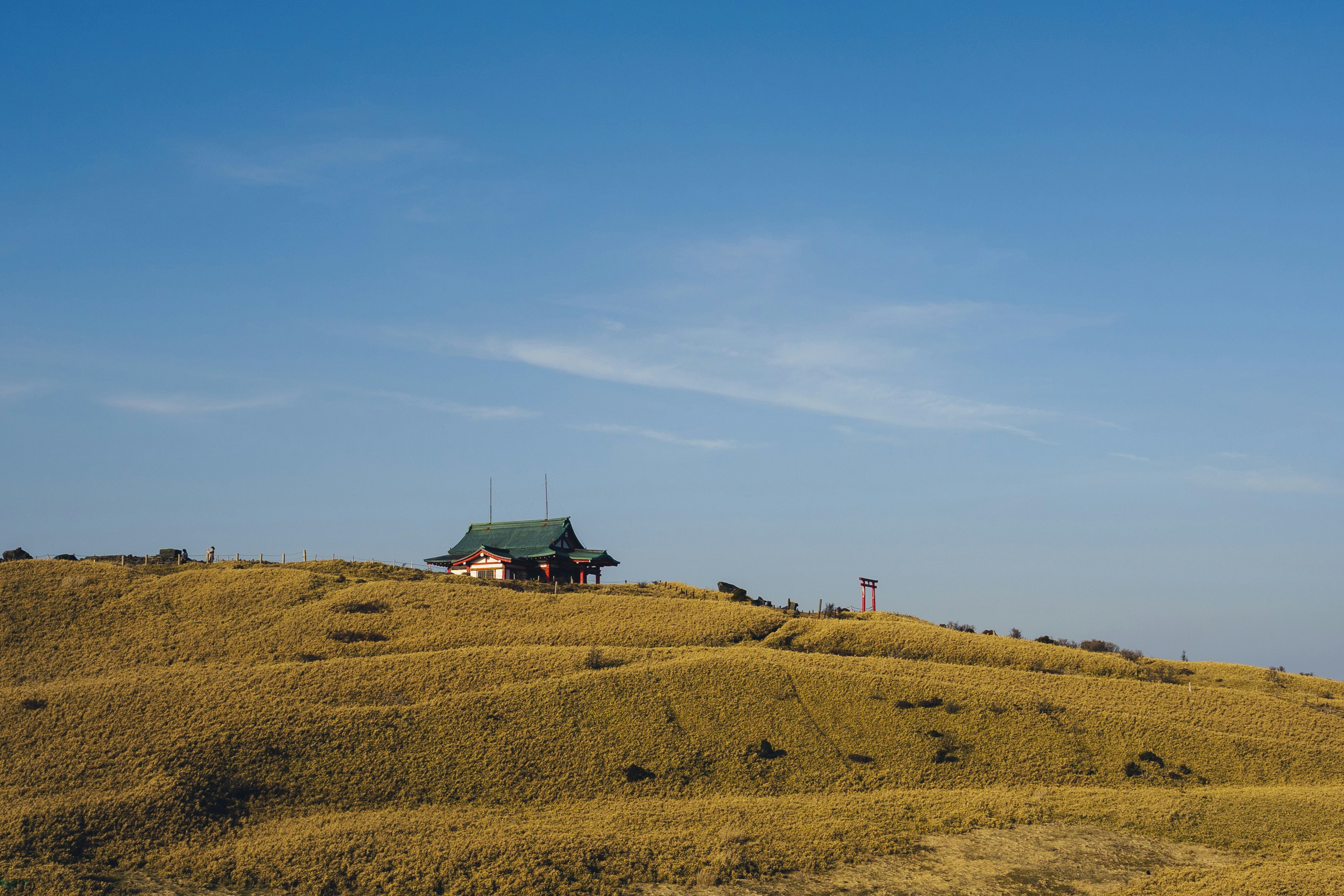 Small building on a grassy hill under blue sky