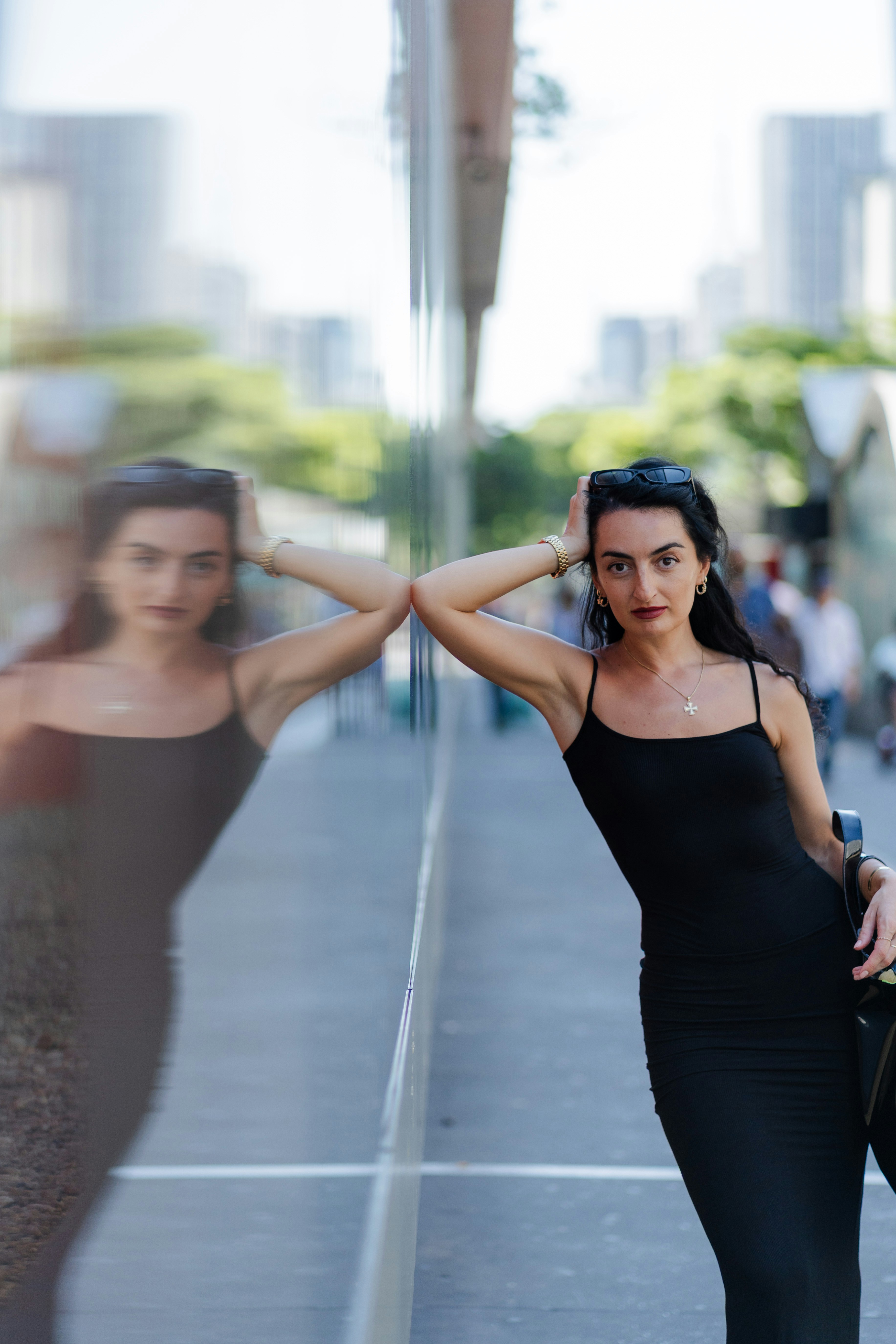 Woman in black dress leaning against reflective surface