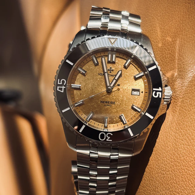 A close-up of a dive watch with a gold dial and rotating bezel