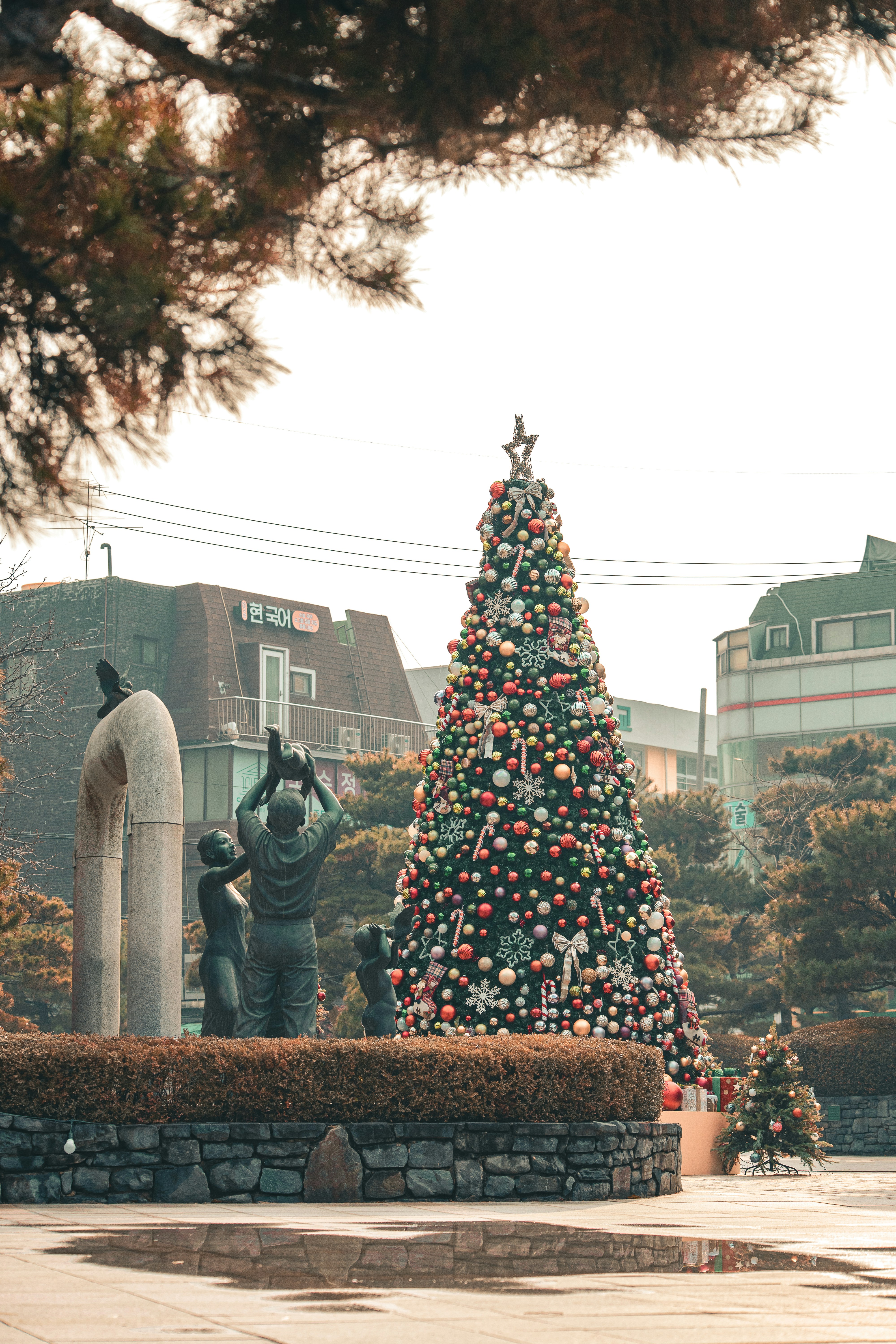 A decorated christmas tree stands near a sculpture.