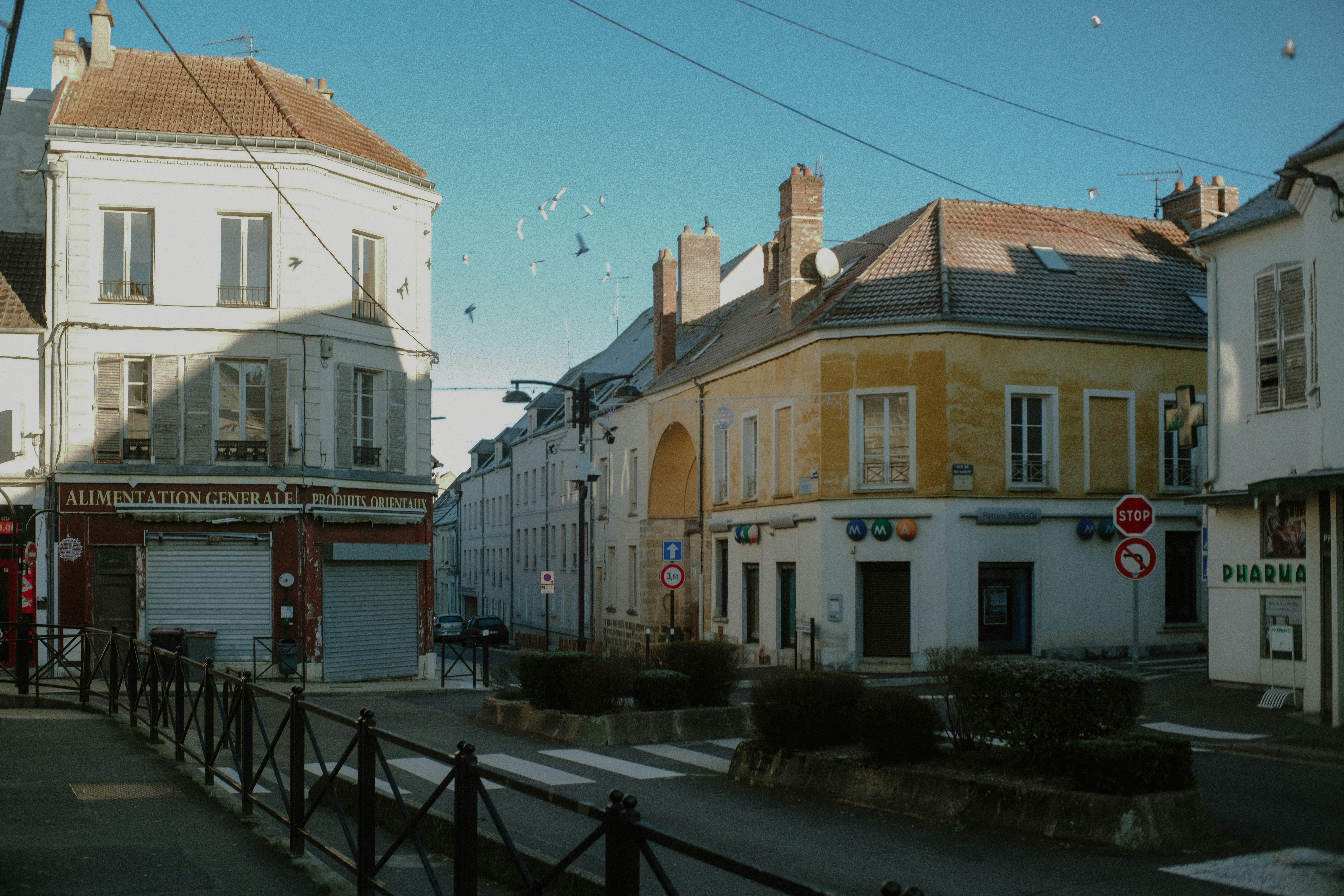 Buildings line a sunny street with a crosswalk.