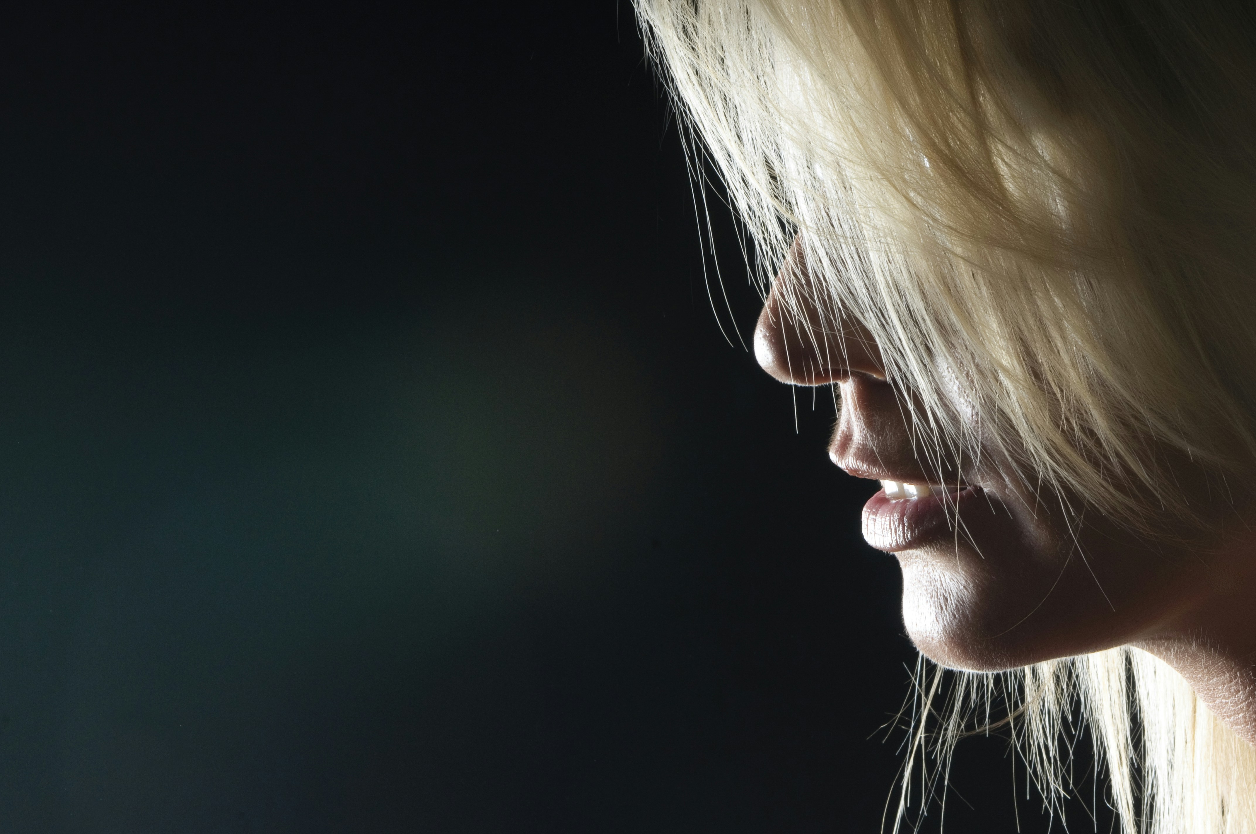 Close-up profile of a blonde woman with hair obscuring face