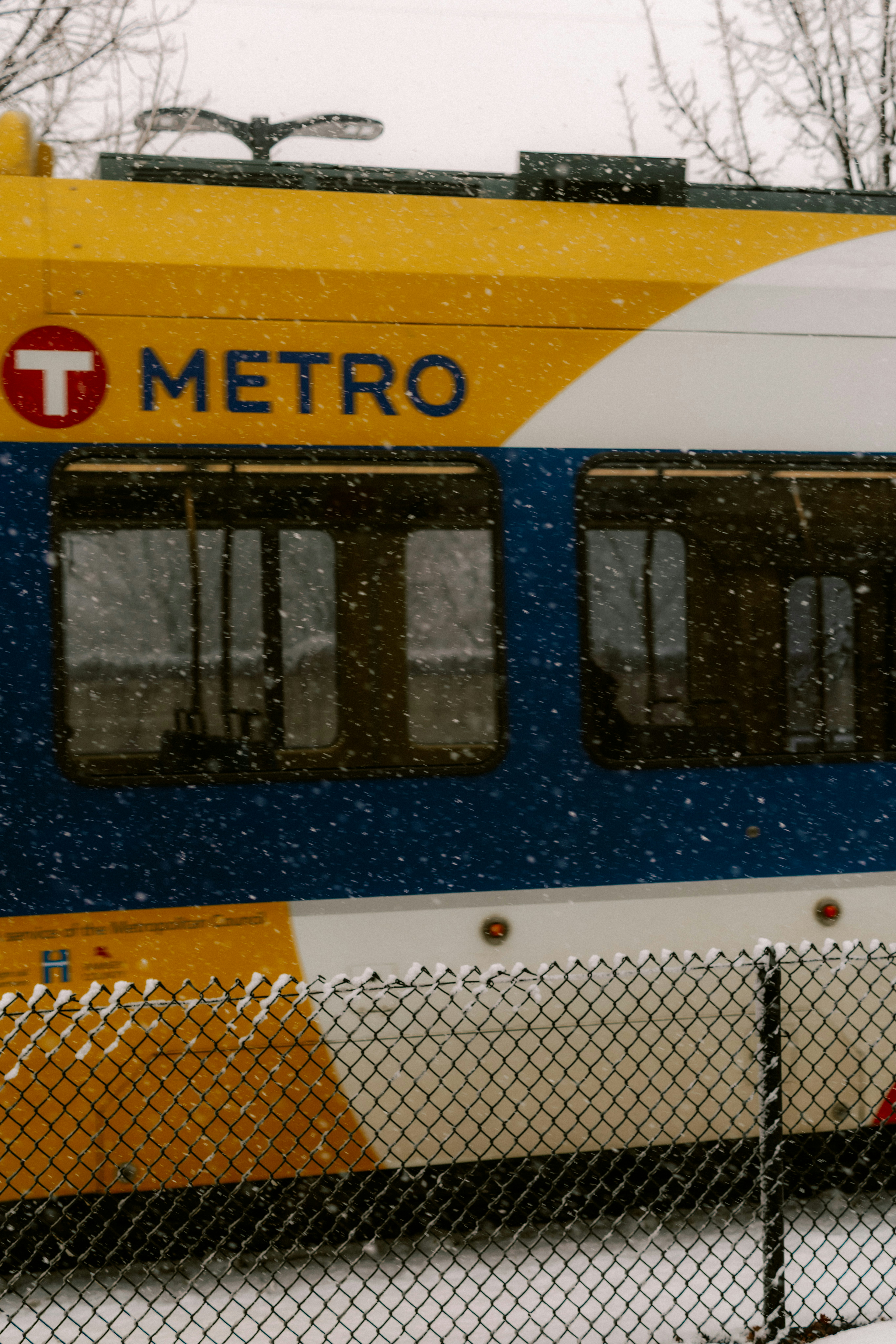 A metro train travels during a snowfall.