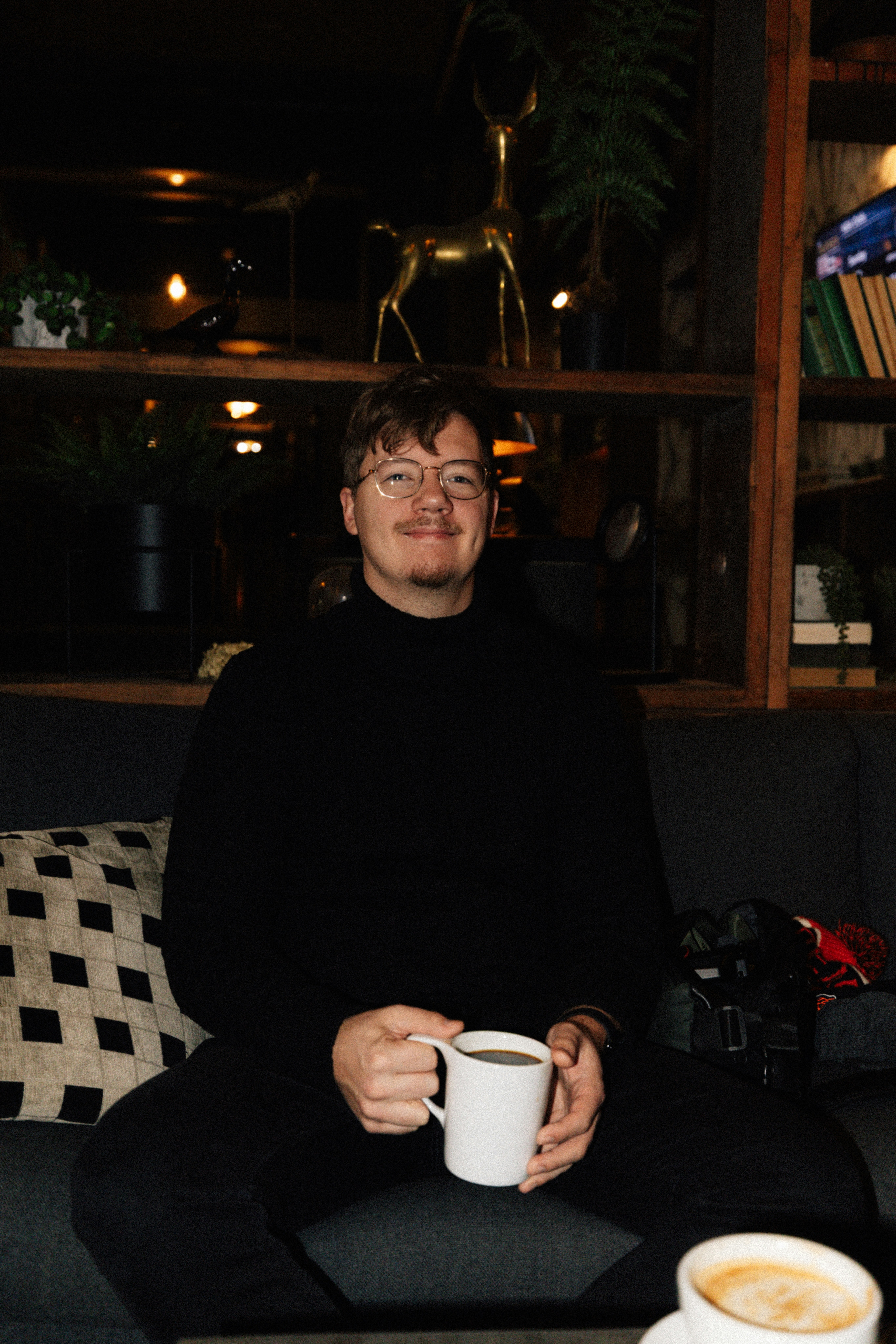 Mann im schwarzen Rollkragenpullover hält eine Kaffeetasse