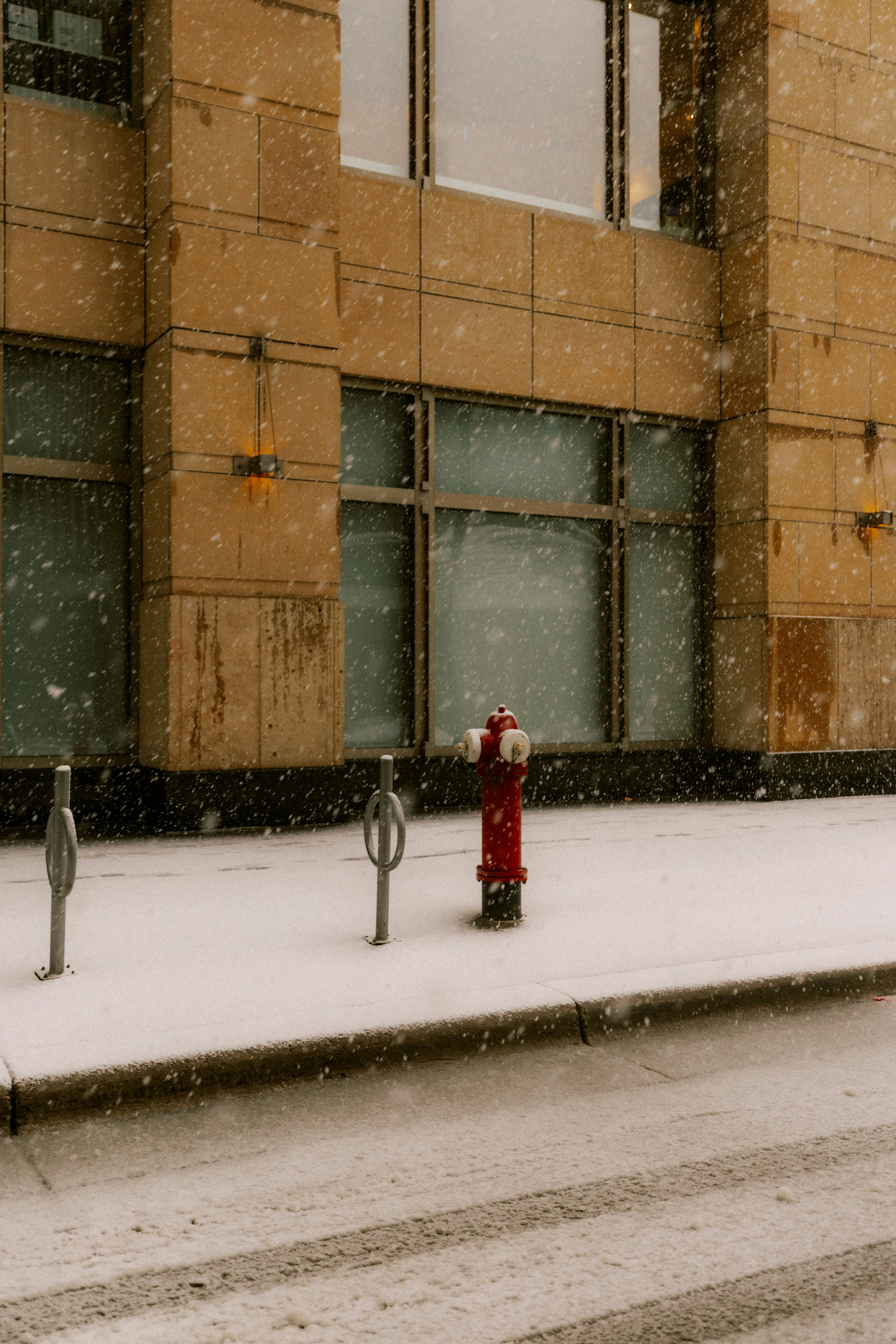 Red fire hydrant on a snowy city sidewalk.