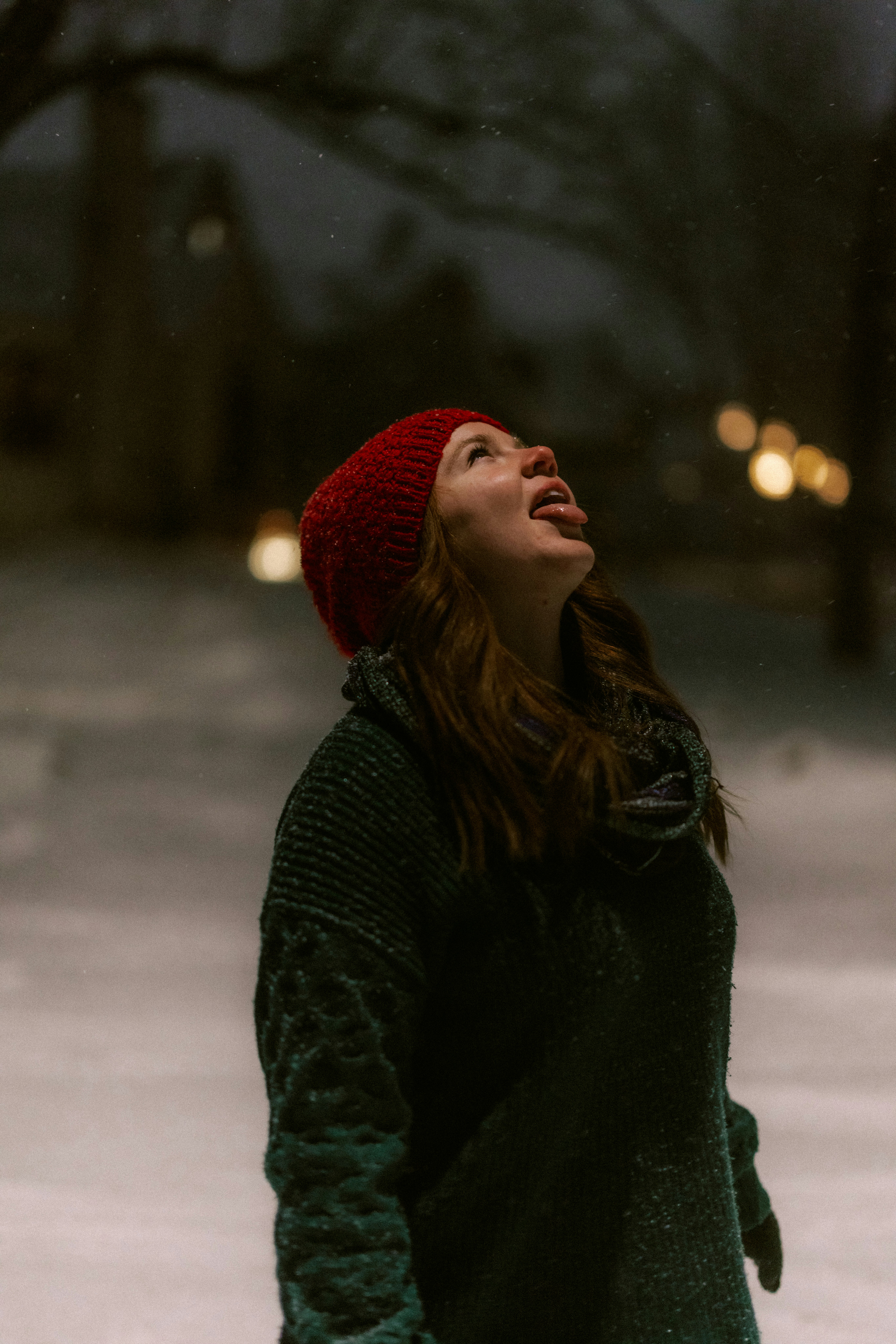 Woman in red hat catching snowflakes on her tongue