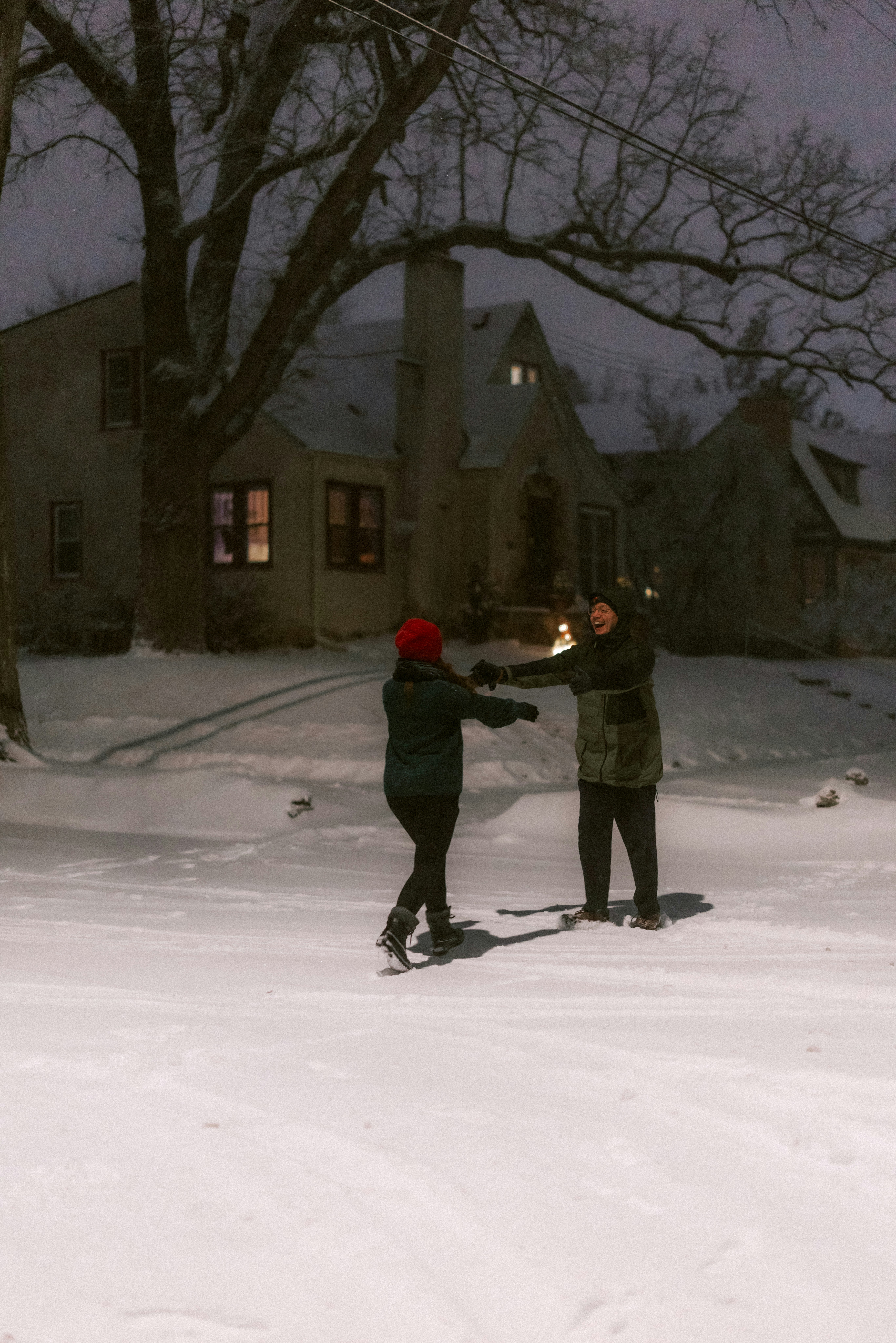 Couple dancing in the snow at night.